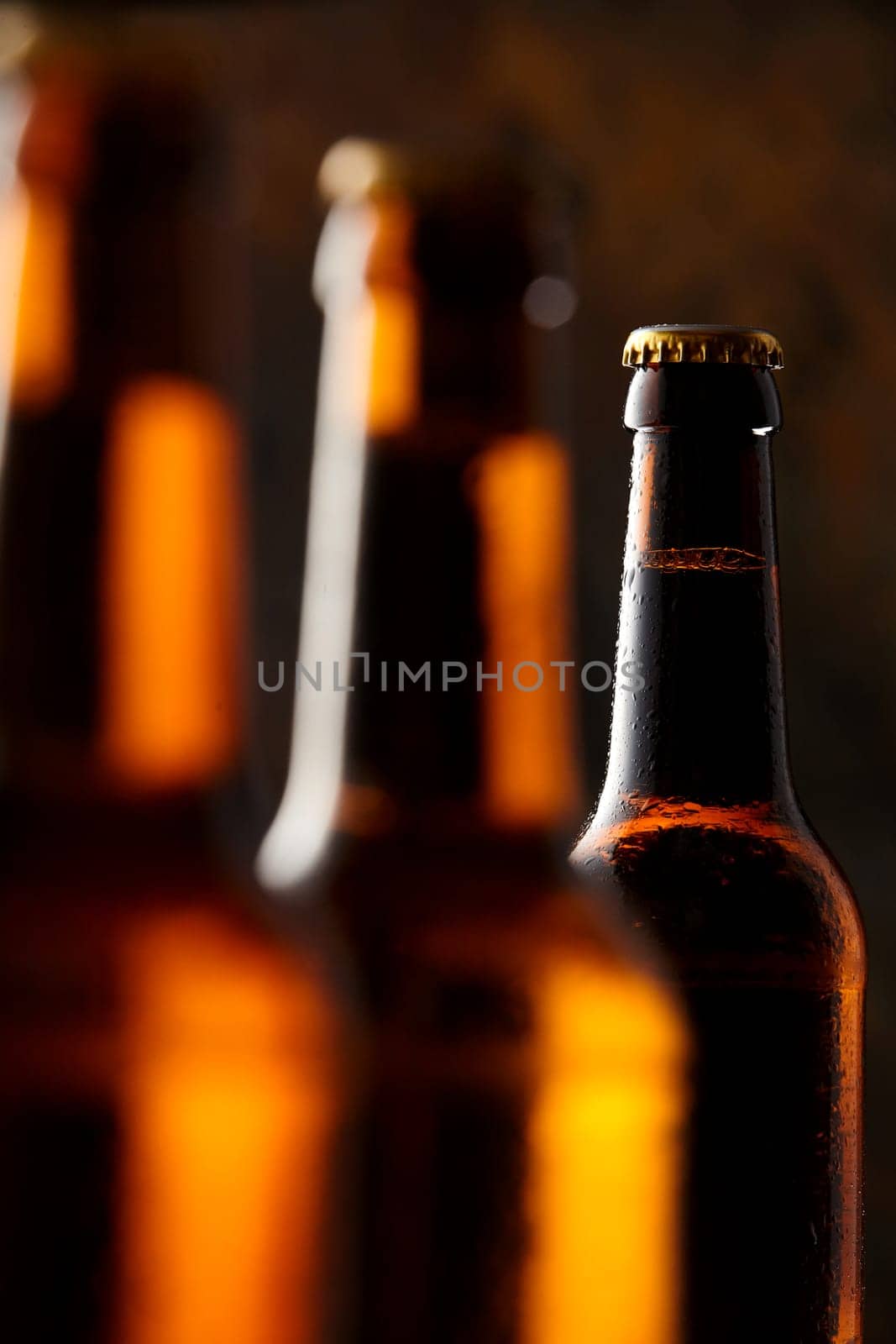 Glowing unlabelled beer bottles in the darkness of a pub or tavern over the Oktoberfest with selective focus to the neck of a bottle in the background
