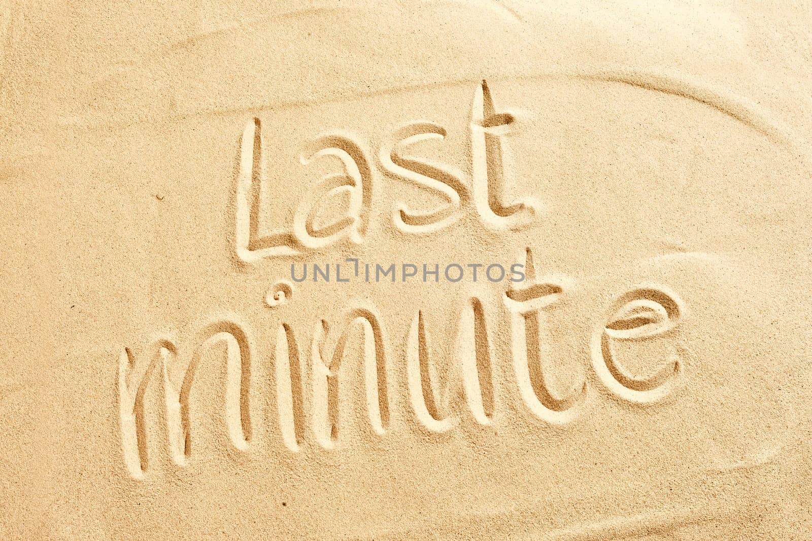 Conceptual image of Last minute holiday deals for a tropical summer vacation with the text handwritten on golden beach sand
