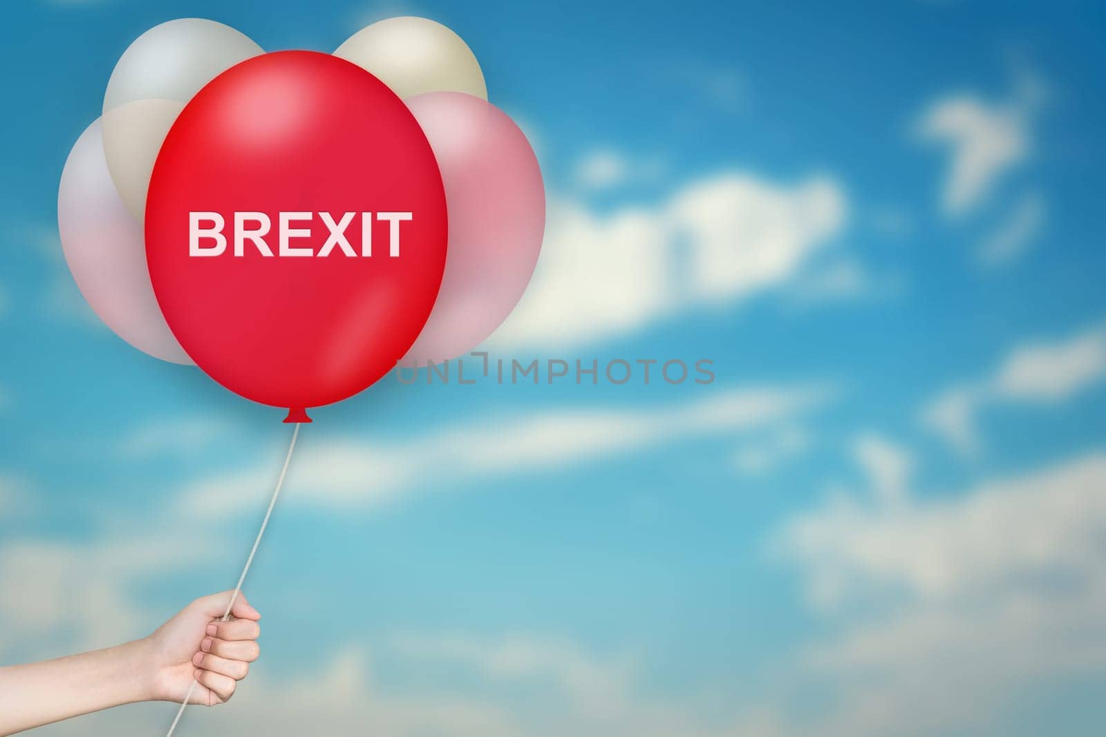 Hand Holding BREXIT or British Exit Balloon with sky blurred background