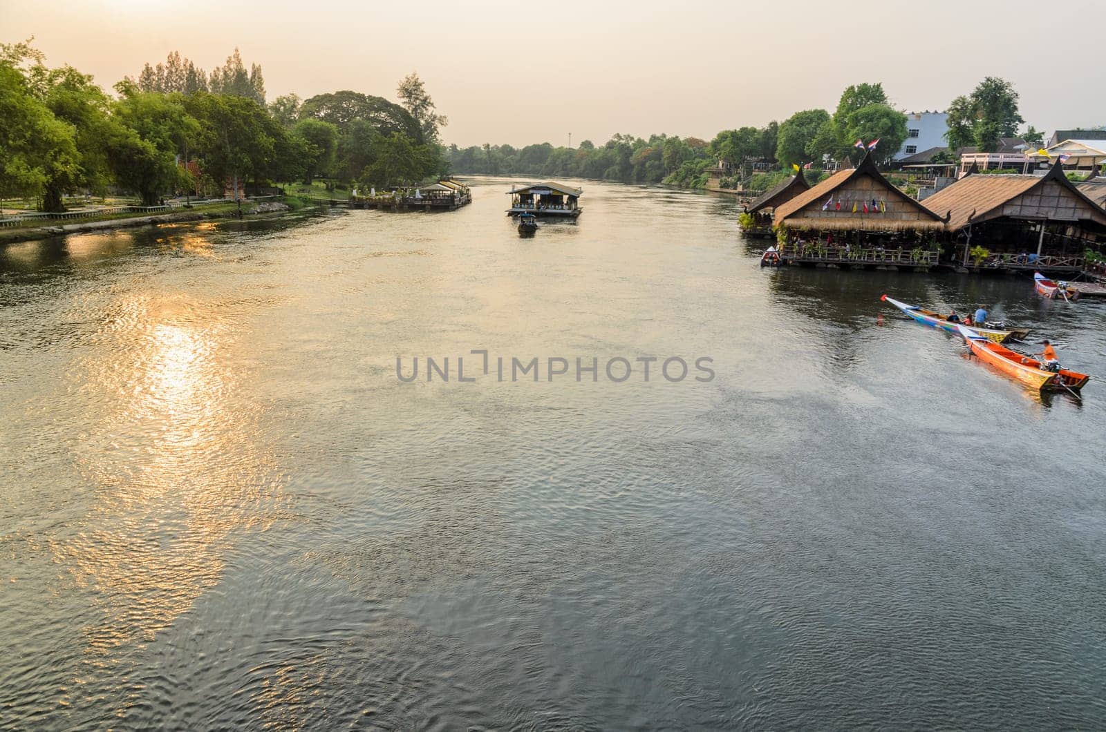 High angle view from bridge, beautiful landscape of Kwai Yai River at sunset and lifestyle of people on the waterfront in Kanchanaburi Province, Thailand