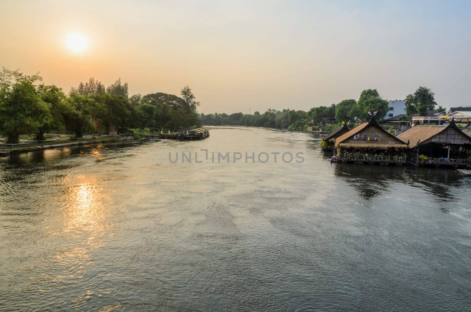 High angle view from bridge, beautiful landscape of Kwai Yai River at sunset and lifestyle of people on the waterfront in Kanchanaburi Province, Thailand