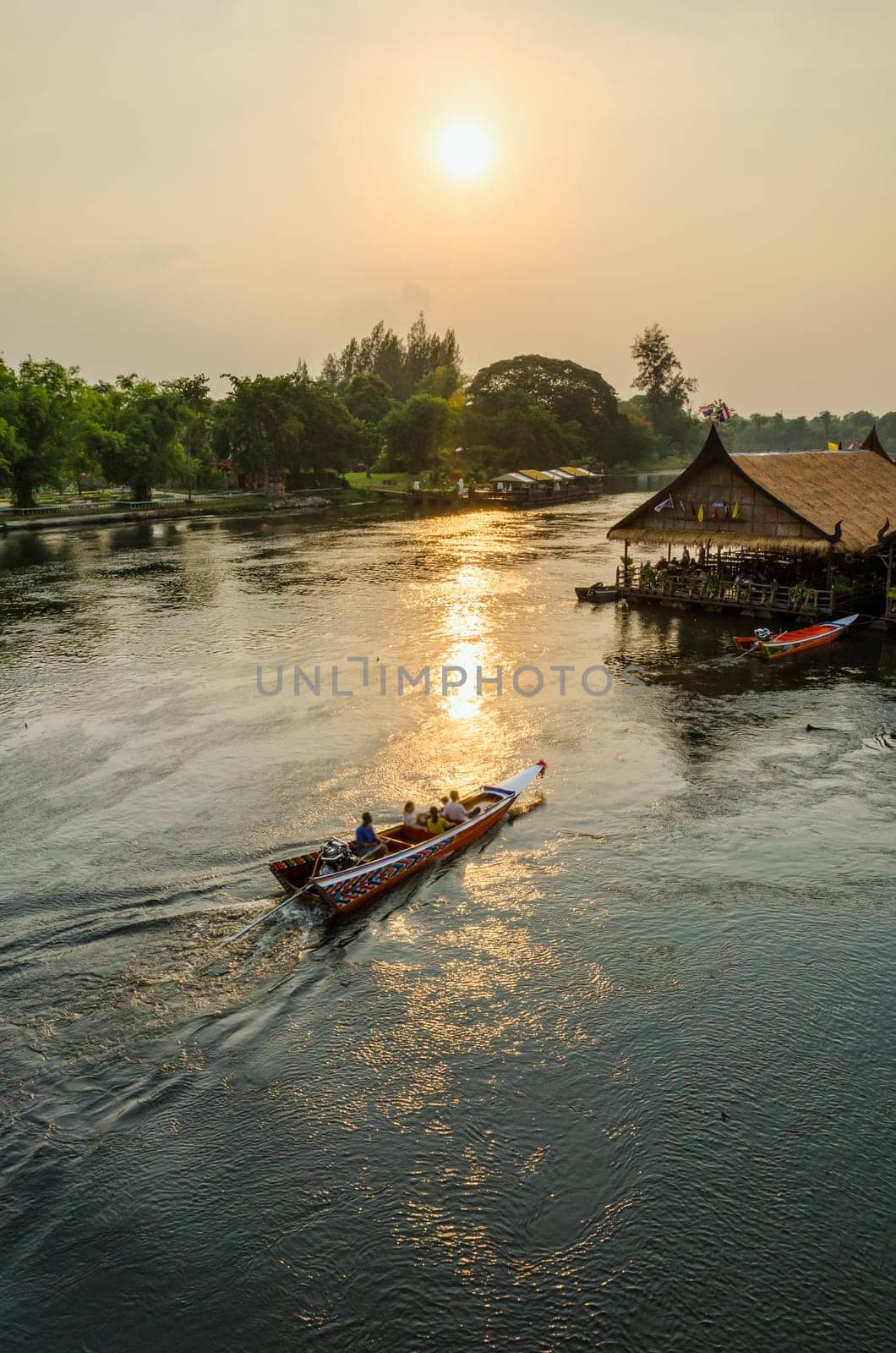 High angle view from bridge, beautiful landscape of Kwai Yai River at sunset and lifestyle of people on the waterfront in Kanchanaburi Province, Thailand