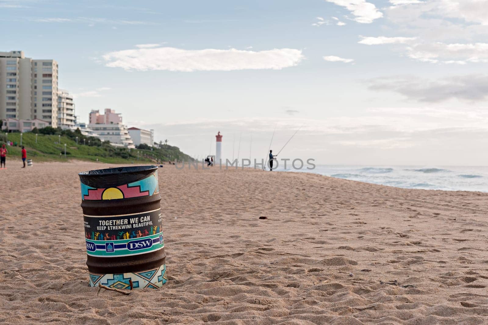DURBAN, SOUTH AFRICA - MARCH 12, 2016: Trash can on the beach near fisherman in Umhlanga Rocks