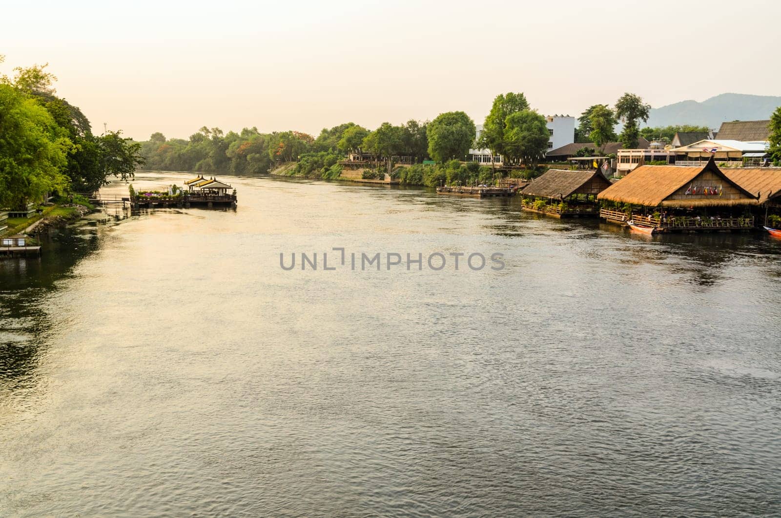 High angle view from bridge, beautiful landscape of Kwai Yai River at sunset and lifestyle of people on the waterfront in Kanchanaburi Province, Thailand