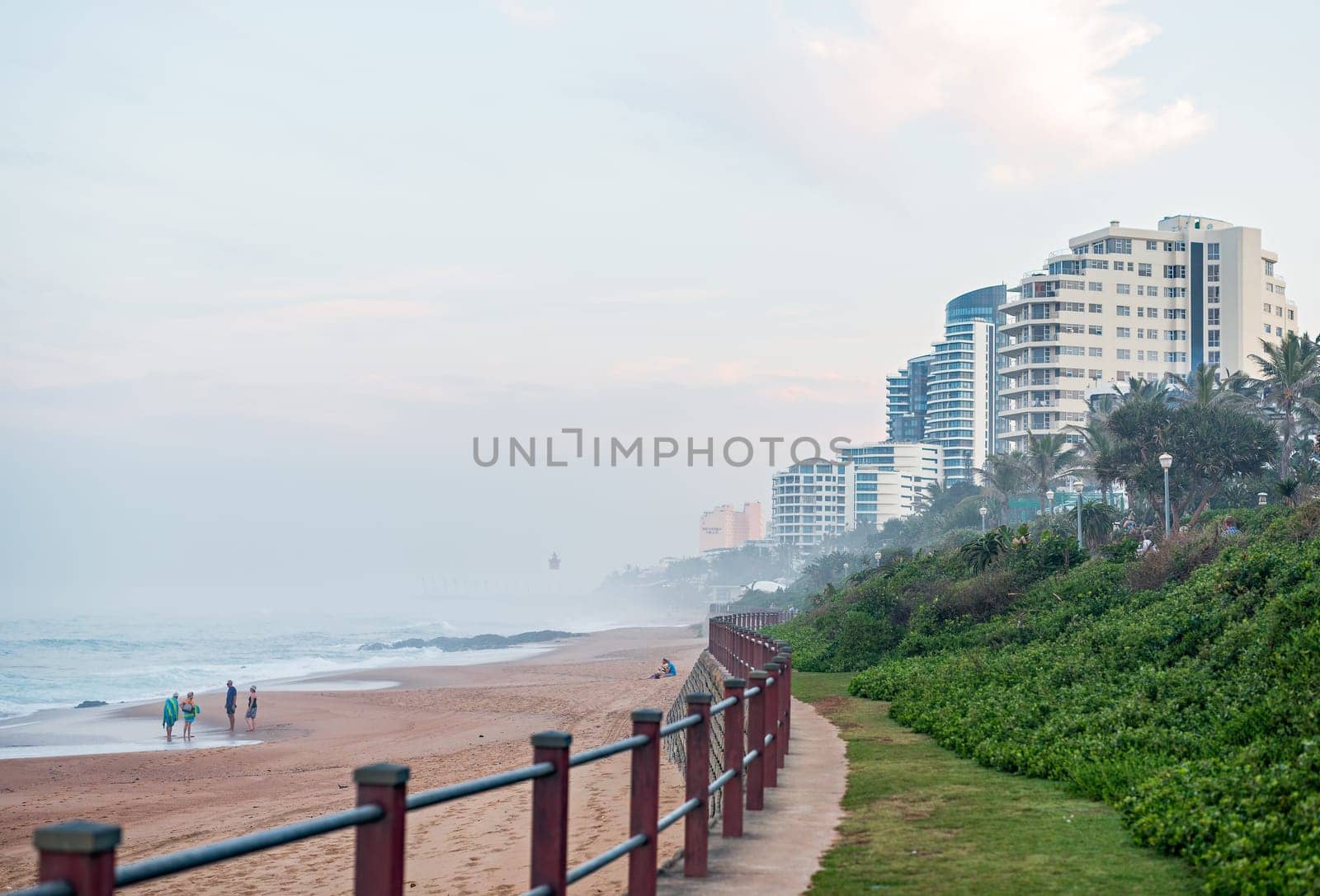 DURBAN, SOUTH AFRICA - MAY 24, 2016: Locals and tourists on the beach and walking along the promenade in Umhlanga Rocks at Sunset