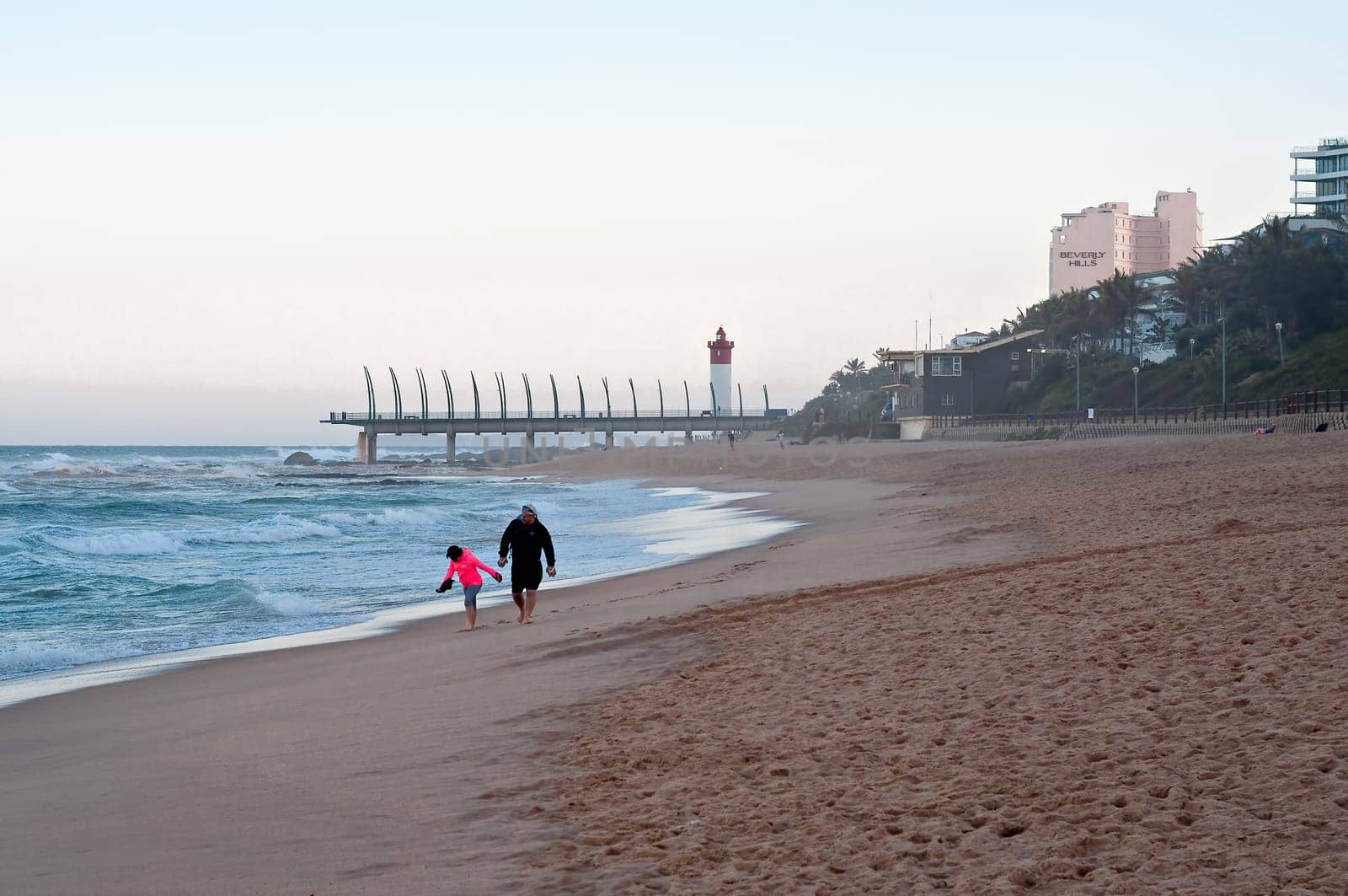 DURBAN, SOUTH AFRICA - JULY 11, 2016: People on the beach at Umhlanga Rocks, with the Millennium Pier and lighthouse in the background.
