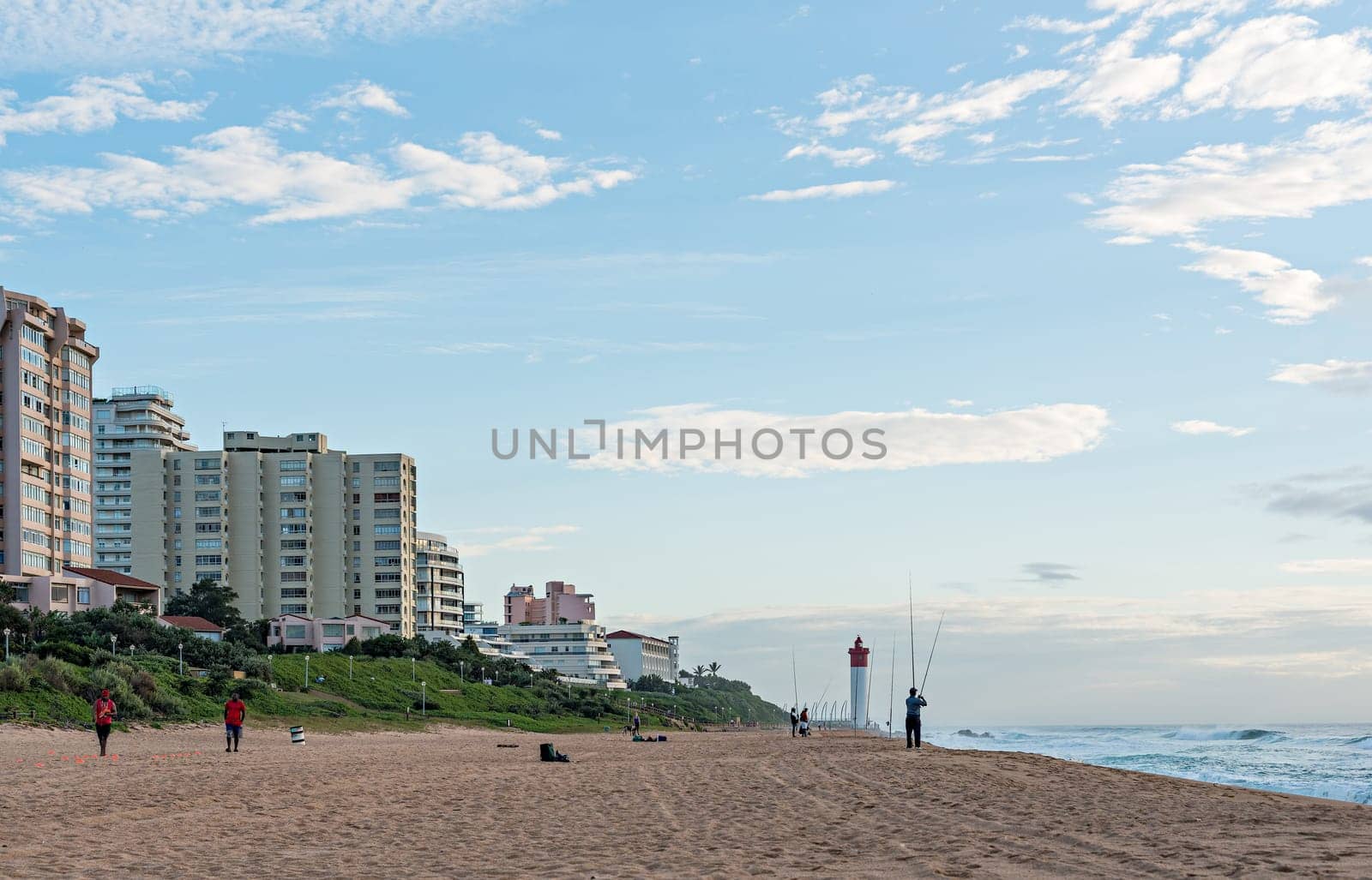 DURBAN, SOUTH AFRICA - MARCH 12, 2016: Anglers and Lifeguards on the Umhlanga Rocks beachfront with Millennium Pier and Lighthouse in the distance