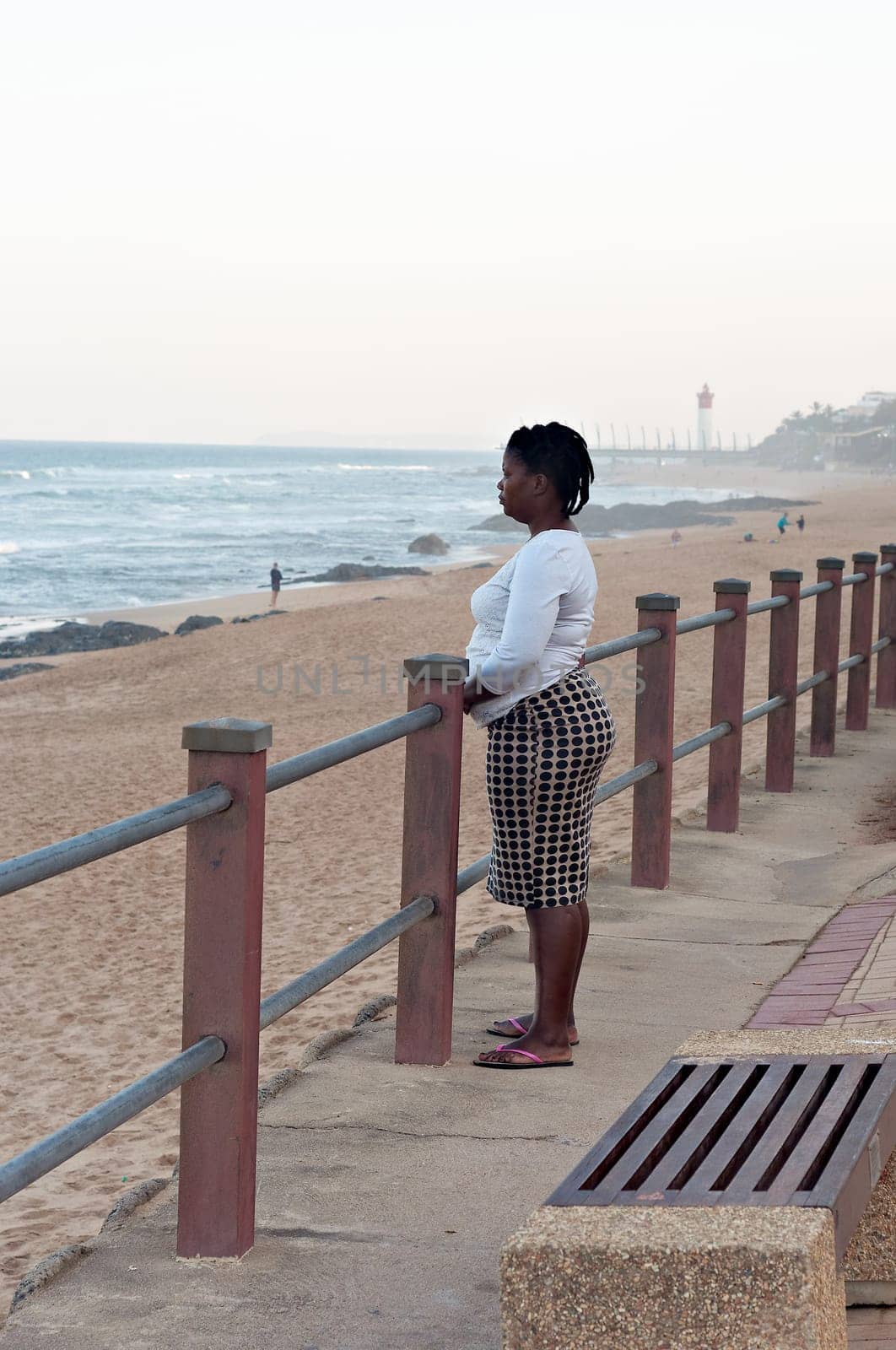 DURBAN, SOUTH AFRICA - JULY 13, 2016: Woman looks out to sea at the beach near the Millennium Pier and lighthouse in Umhlanga Rocks