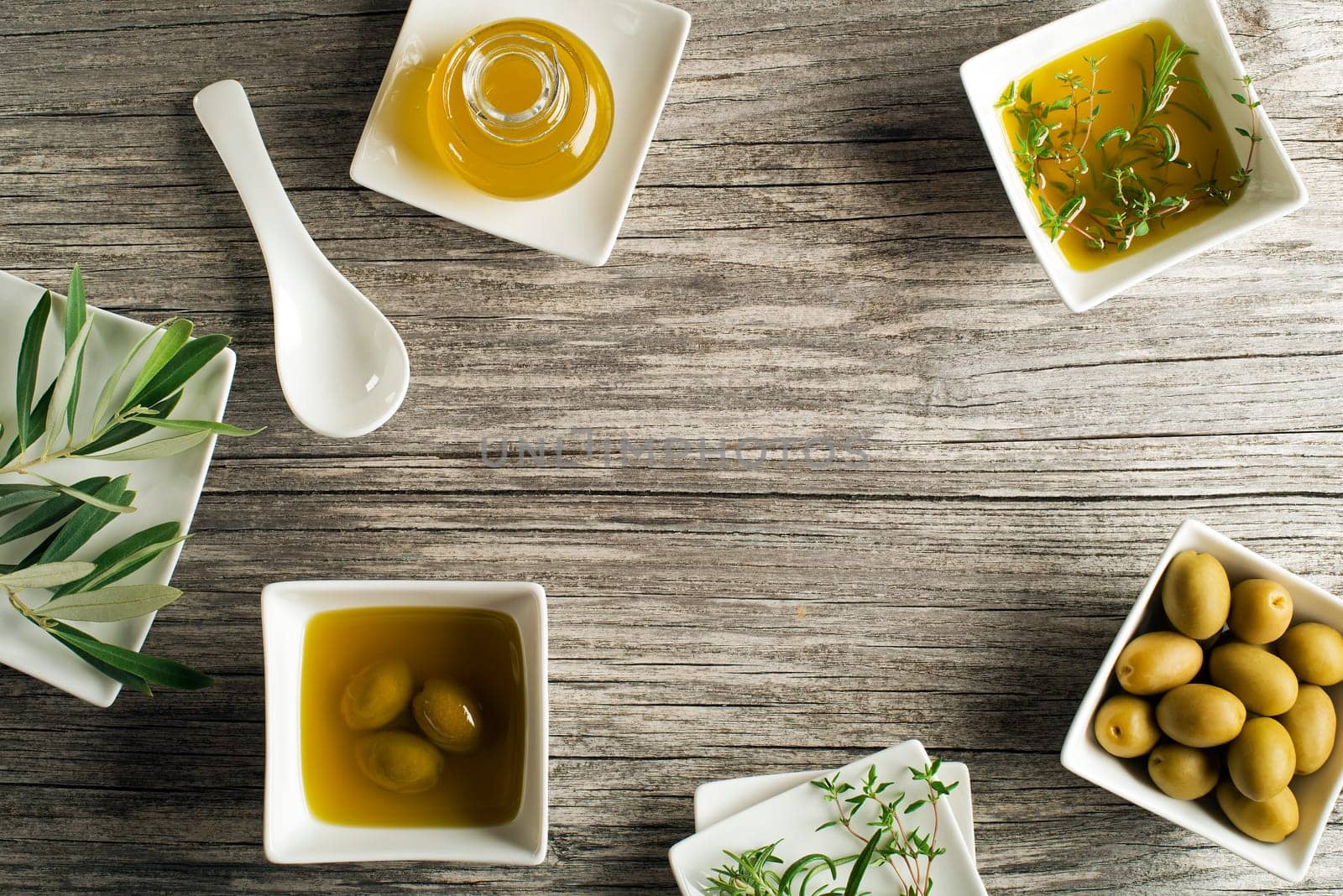 Olive oil with fresh herbs on wooden background