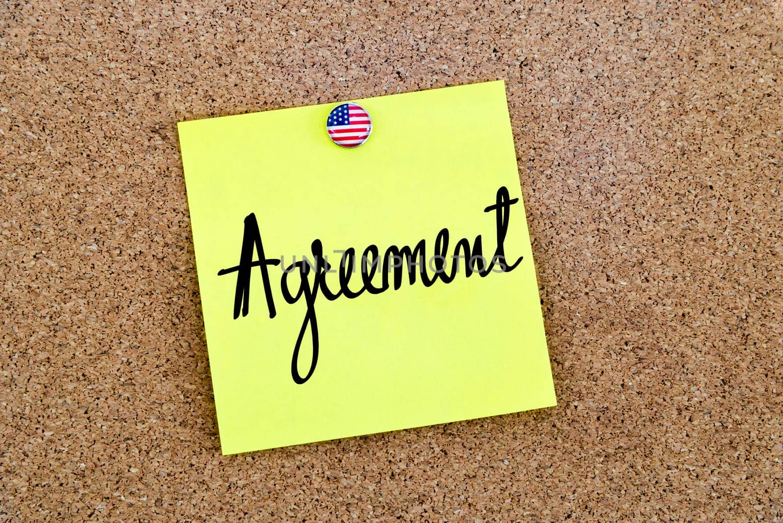 Written text Agreement over yellow paper note pinned on cork board