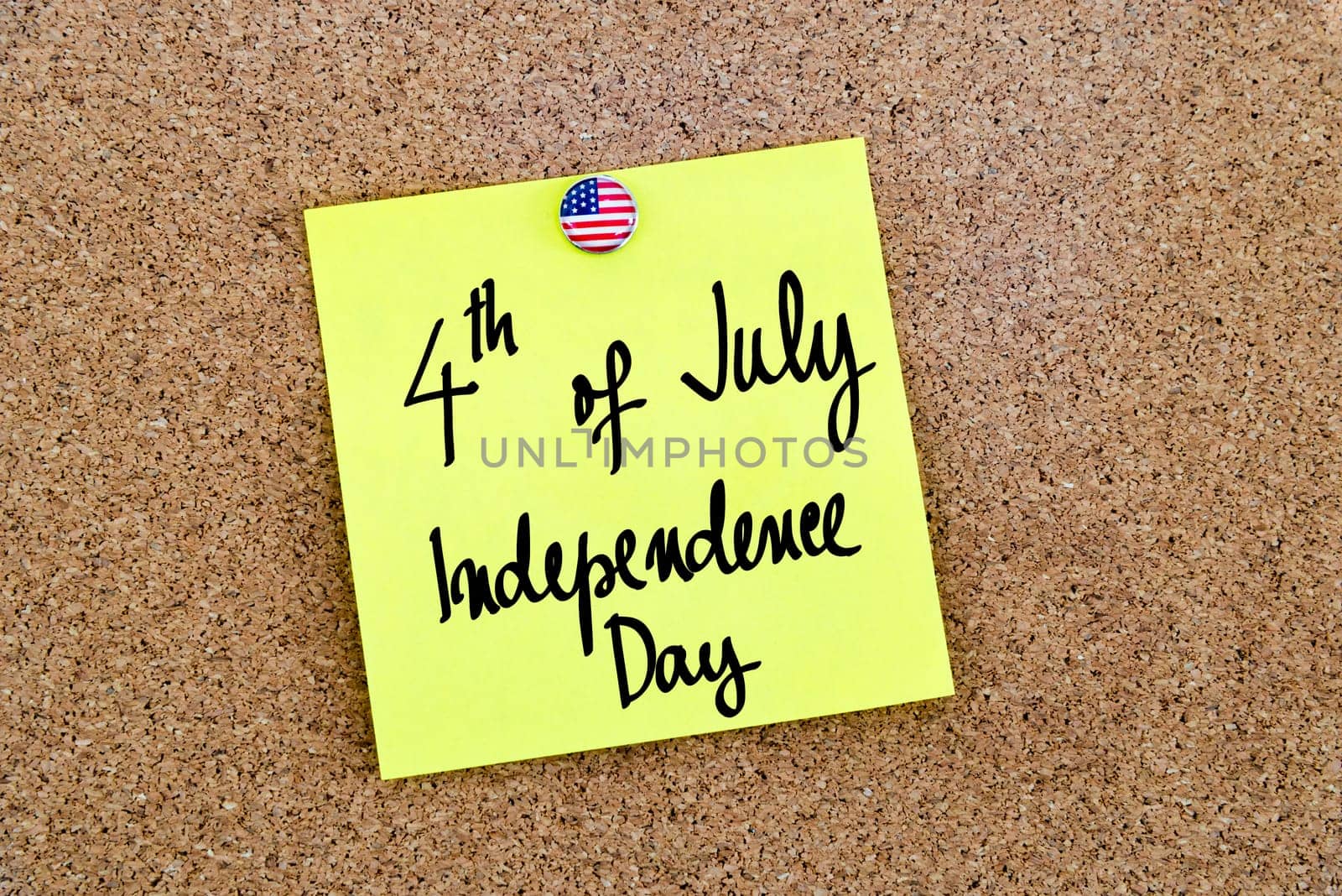 Written text 4th of July Independence Day over yellow paper note pinned on cork board