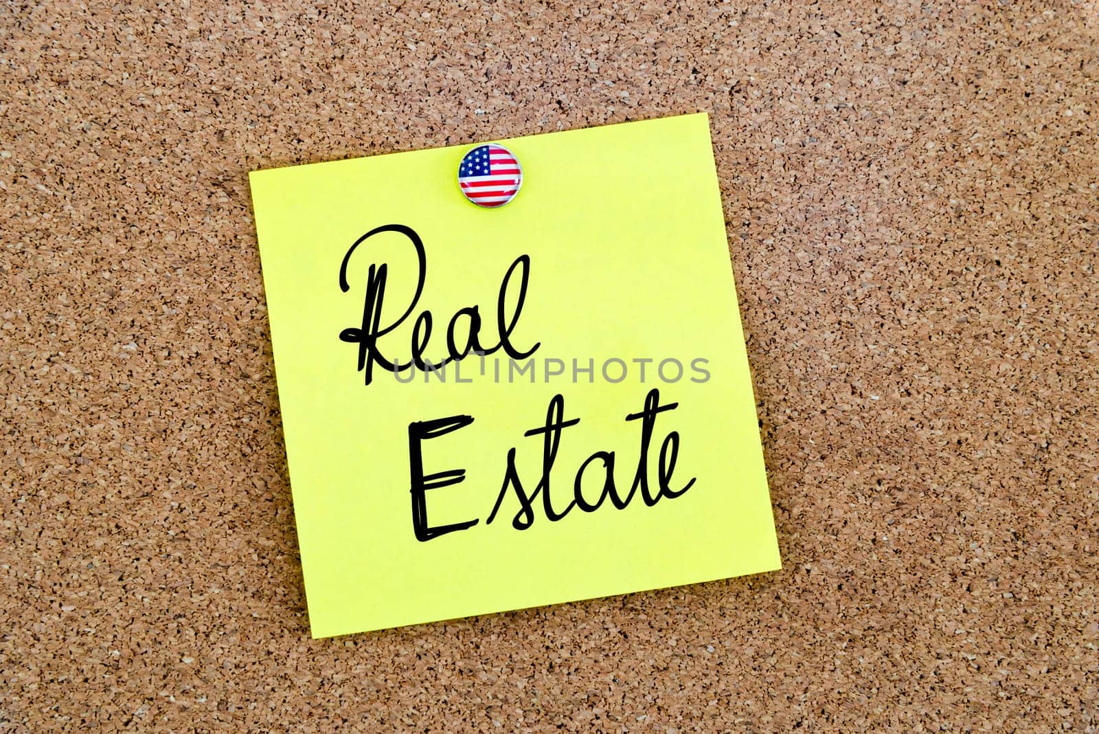 Written text Real Estate over yellow paper note pinned on cork board