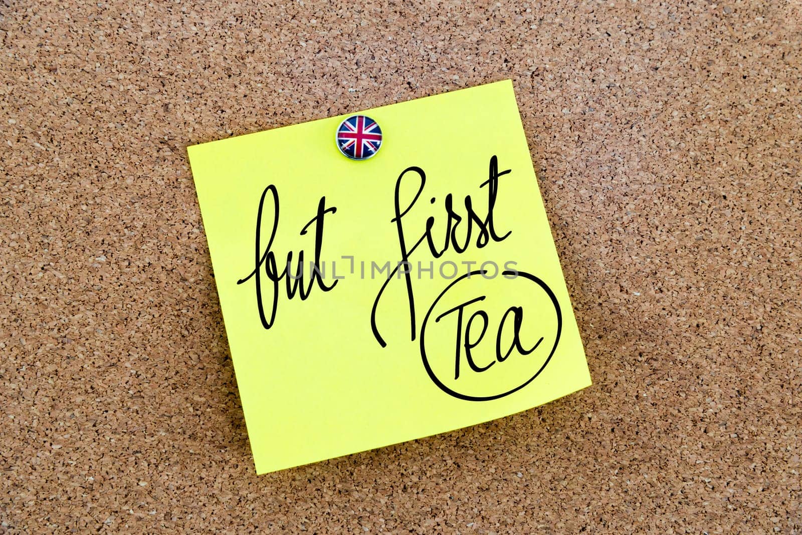 Yellow paper note pinned on cork board with Great Britain flag thumbtack, written text But First Tea, British Business concept