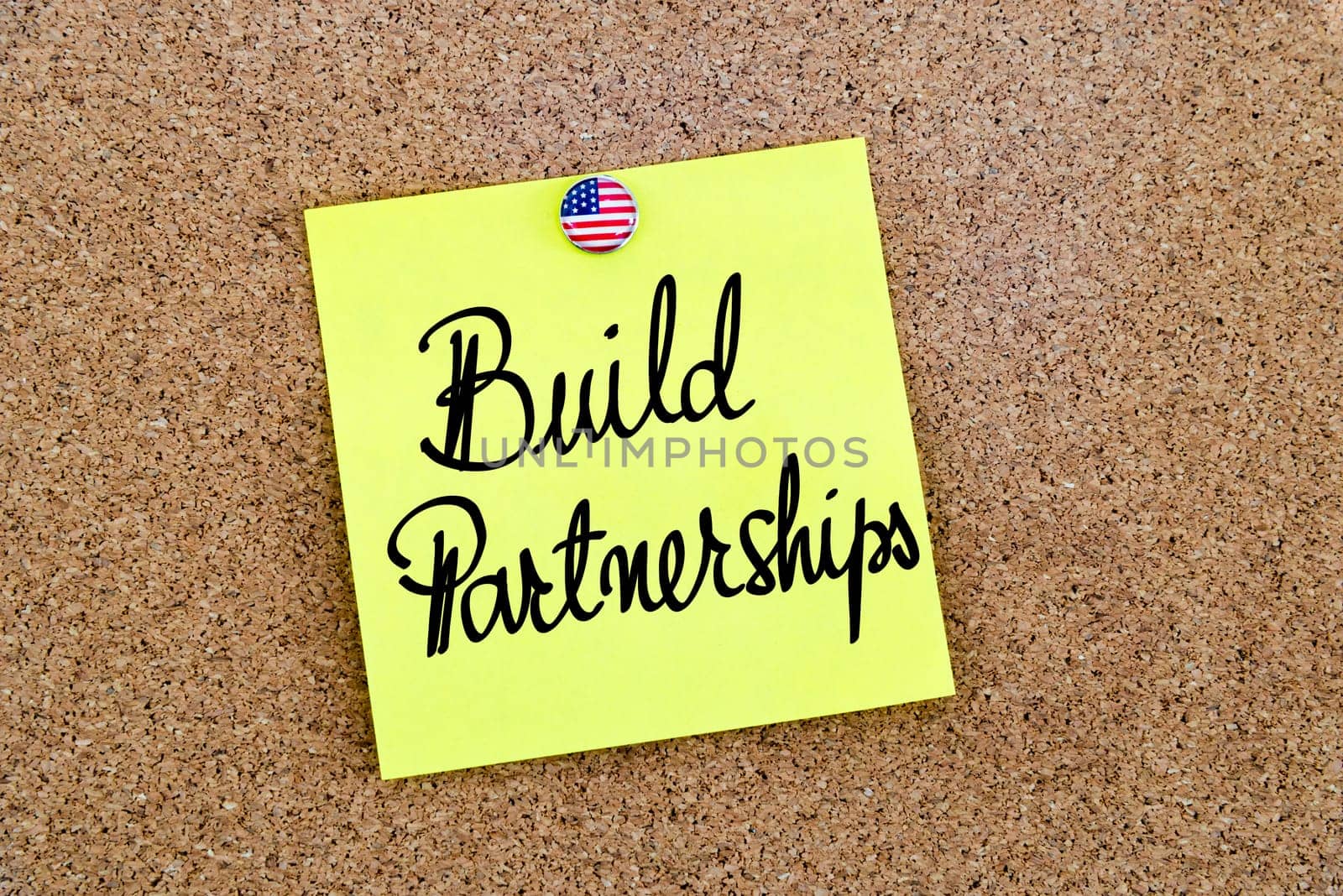 Written text Build Partnerships over yellow paper note pinned on cork board