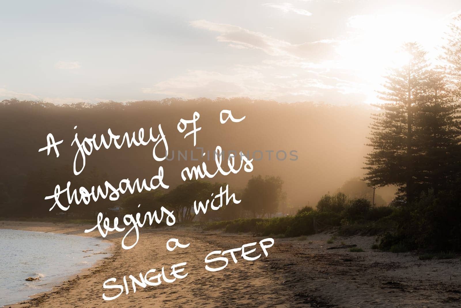 A Journey Of A Thousand Miles Begins With A Single Step message. Handwritten motivational text over sunset calm sunny beach background with vintage filter applied