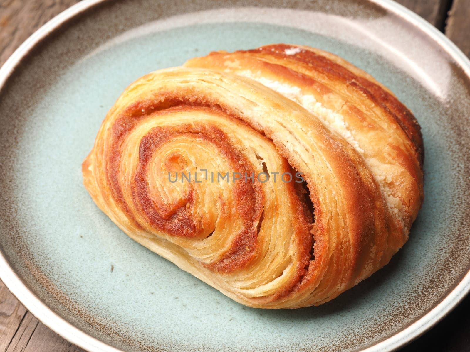Delicious pastry with cinnamon on a blue rustic plate