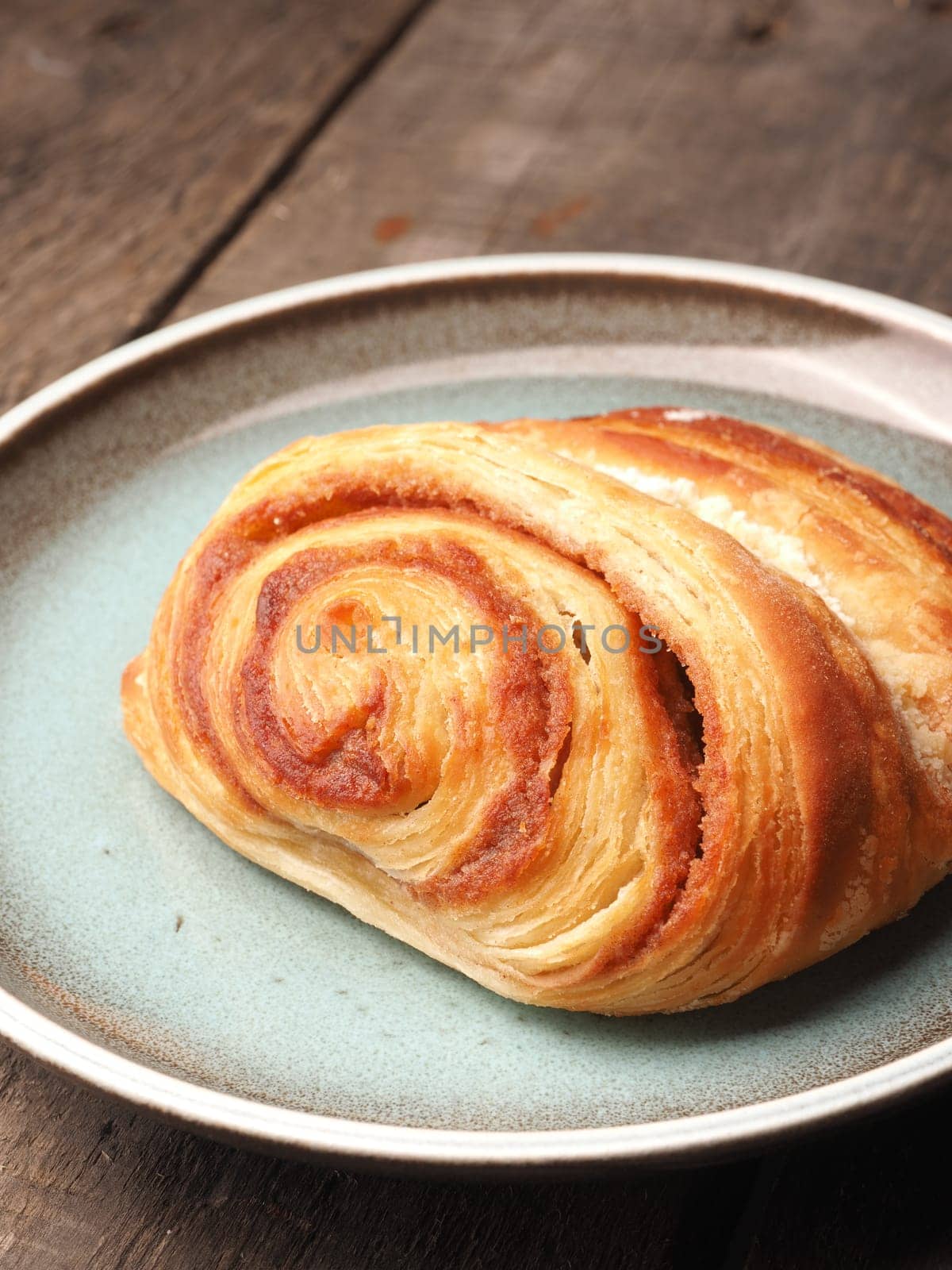 Sweet cinnamon pastry on a plate with a rustic wooden background