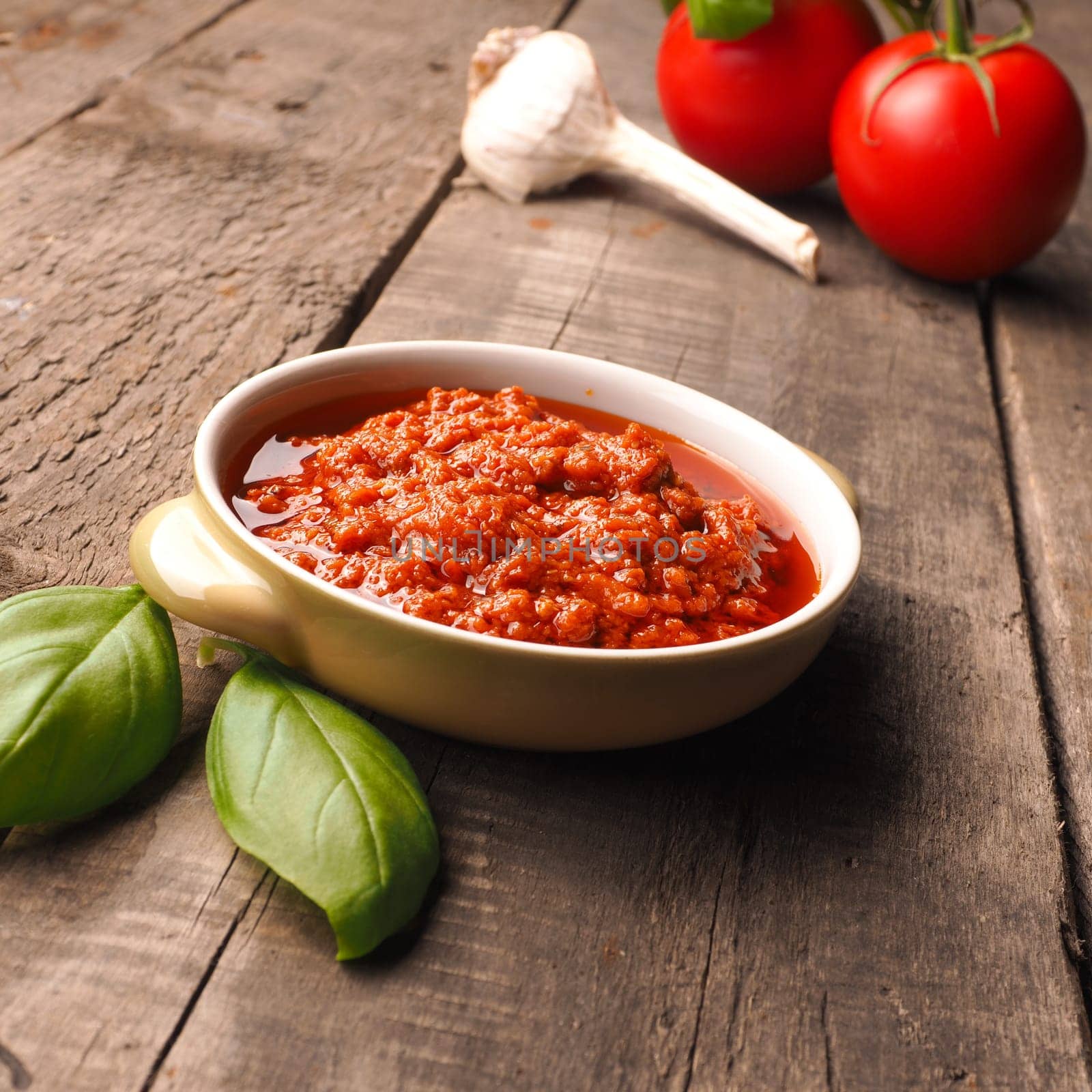 Homemade red pesto in a bowl with fresh tomatoes and garlic