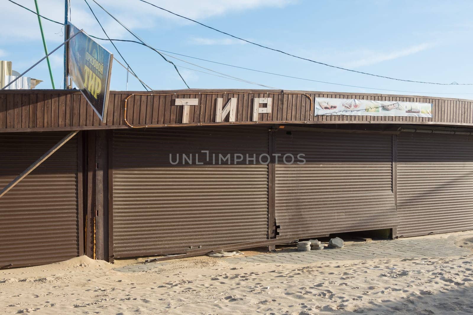 Vityazevo, Russia - March 7, 2016: meadow covered pavilion with a broken roller shutters and the signboard "Tir"", sanded in the offseason"