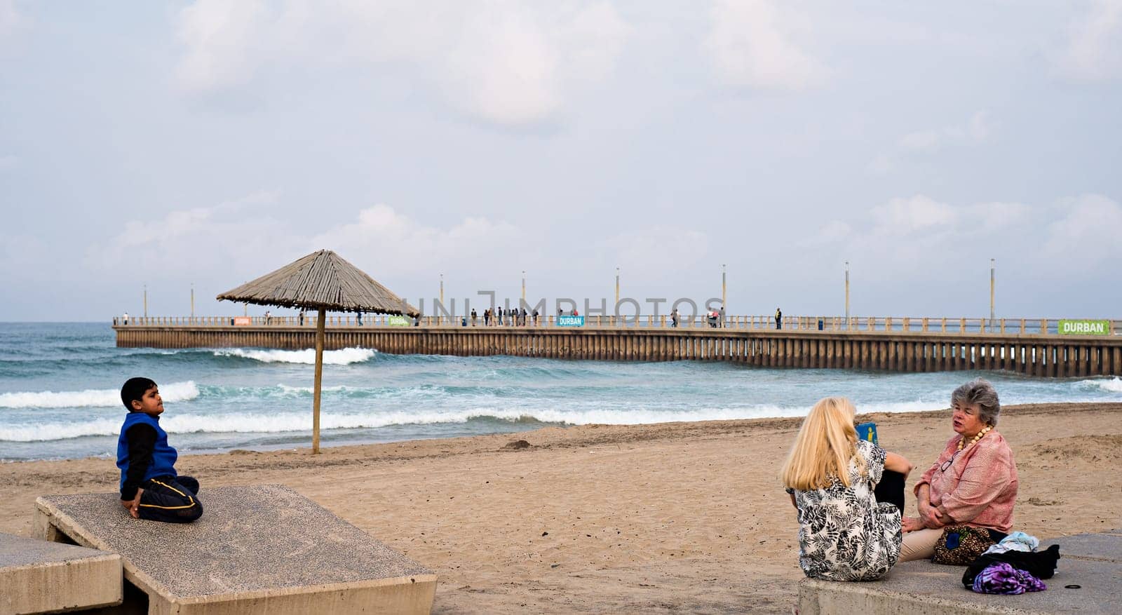 DURBAN, SOUTH AFRICA - AUGUST 17, 2015: People sitting near the pier at North Beach on the Golden Mile promenade.