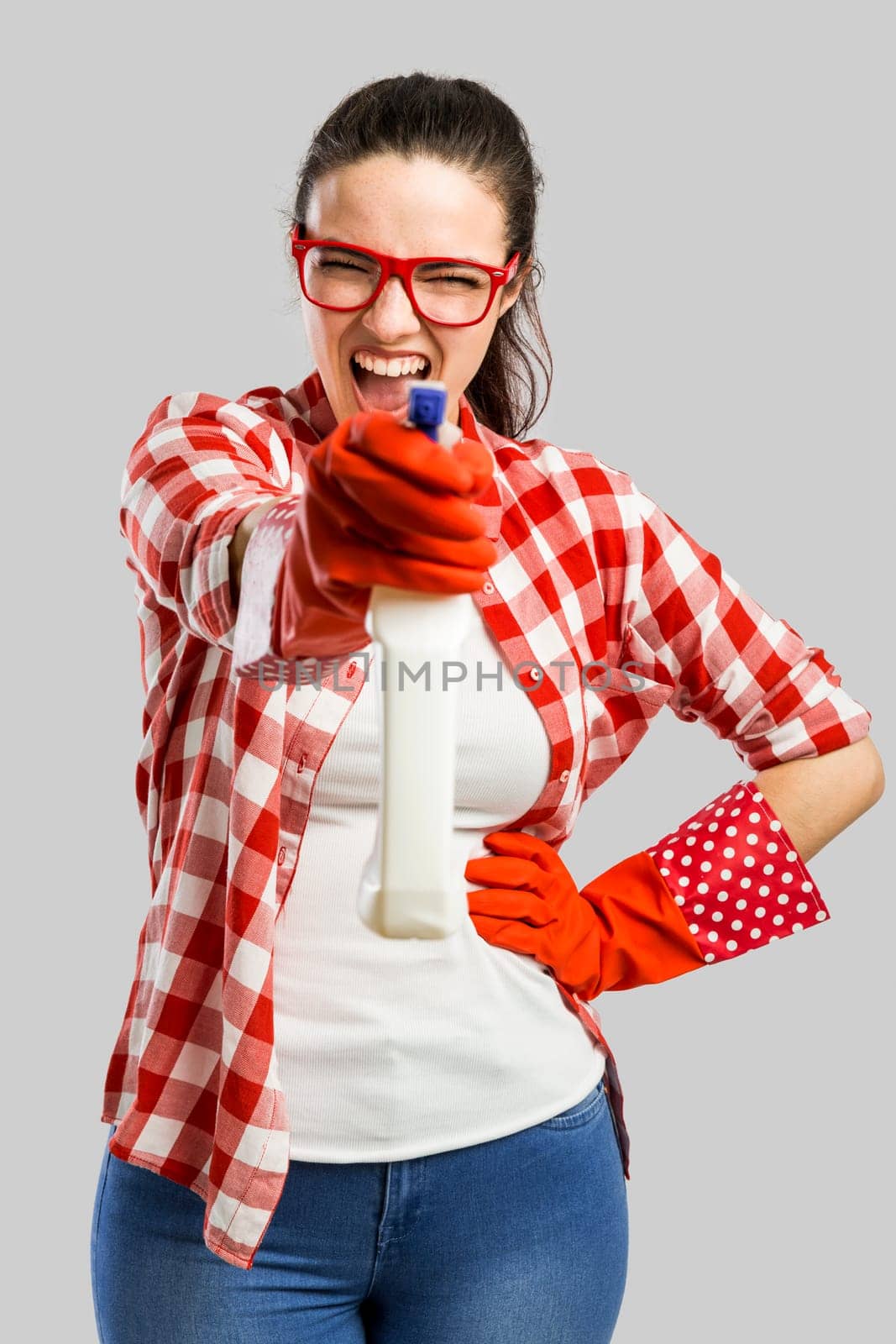 Pretty woman wearing gloves, using a cleaning spray and cleaning the house