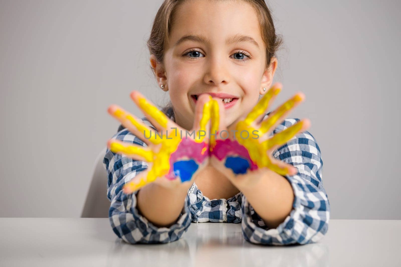 Cute smiling little girl with hands in paint