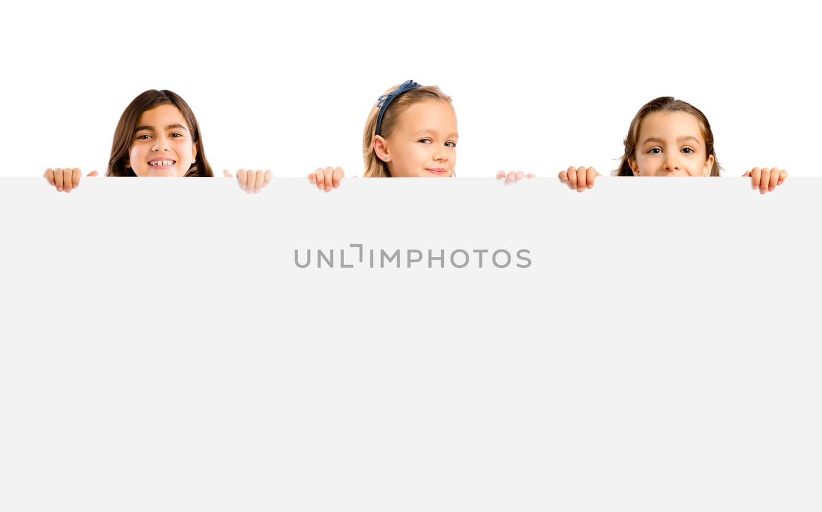 Cute litle girls holding a big white board with copyspace.