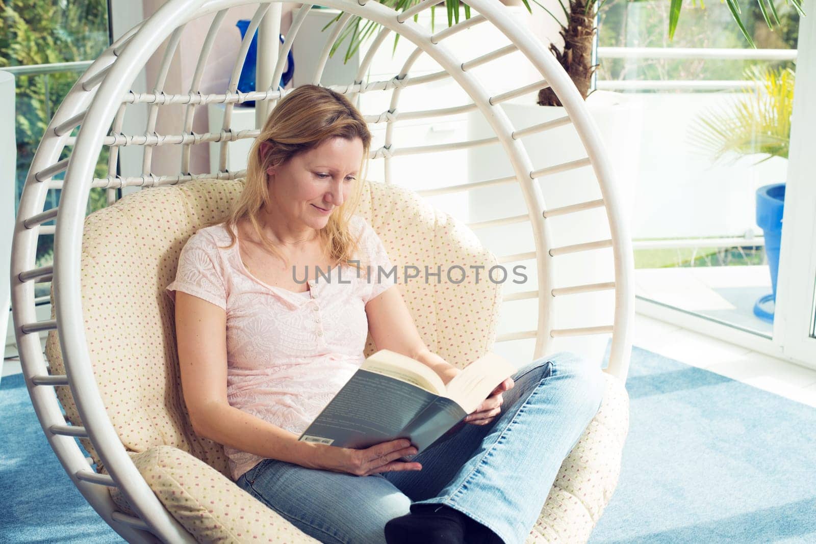 blond woman sitting in chair and reading a book