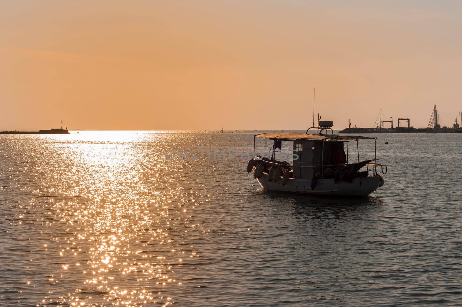 Professional fishing boat leaves the harbour at sunset