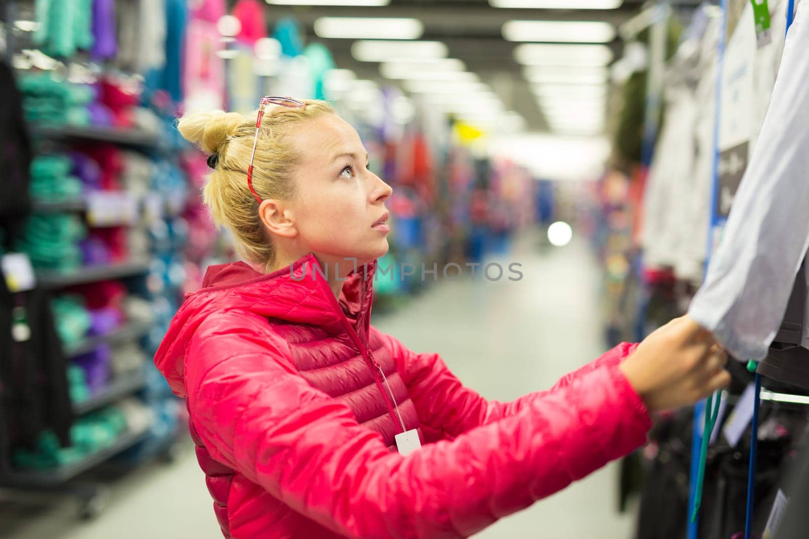 Beautiful caucasian woman shopping sportswear in sports store.