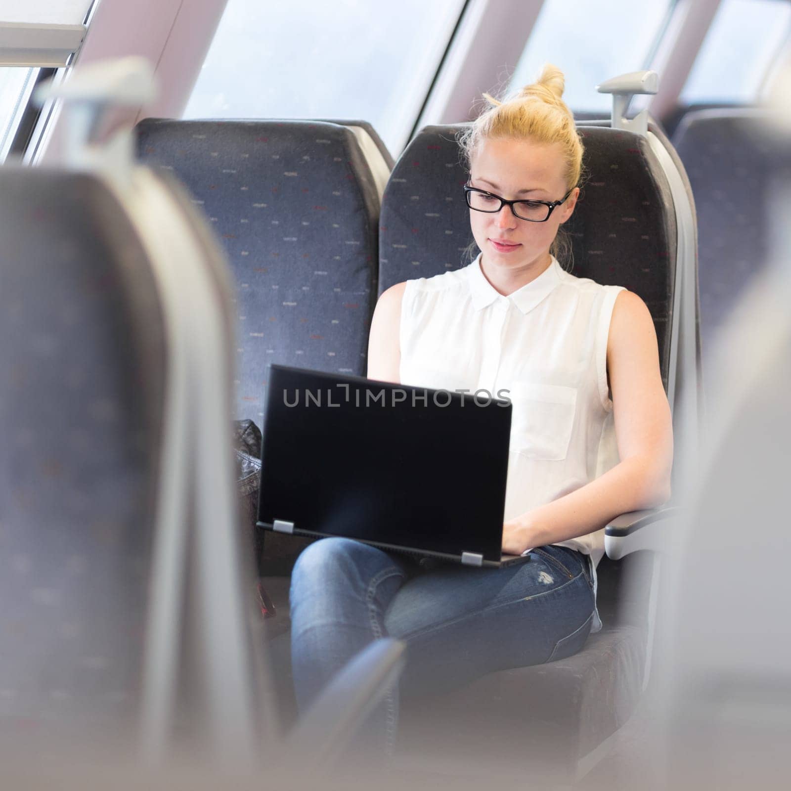 Businesswoman sitting and traveling by train working on laptop. Business travel concept.