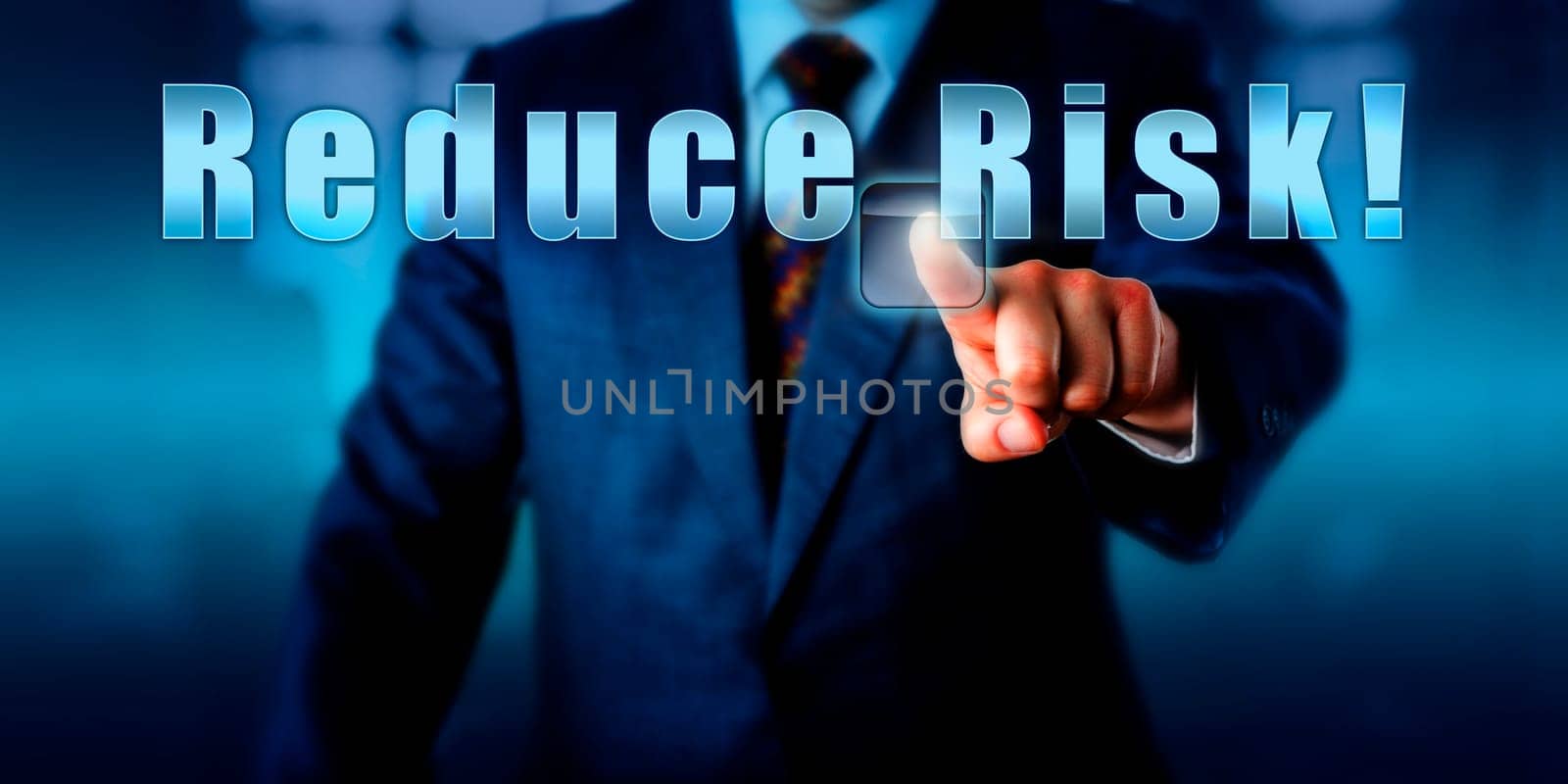 Corporate Manager is pressing Reduce Risk! on an interactive touch screen. Business objective concept, call to action, motivational metaphor and professional advice. Torso shot of man in blue suit.