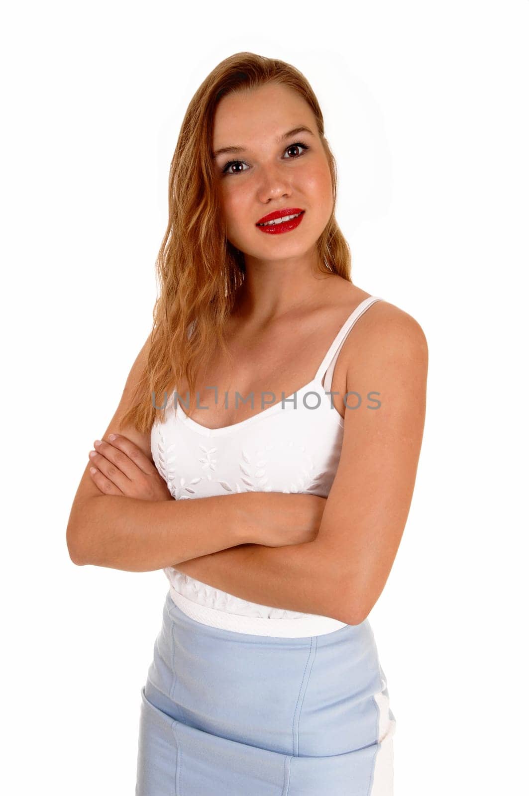 A beautiful slim blond woman standing isolated for white background.looking into the camera with her arms crossed..