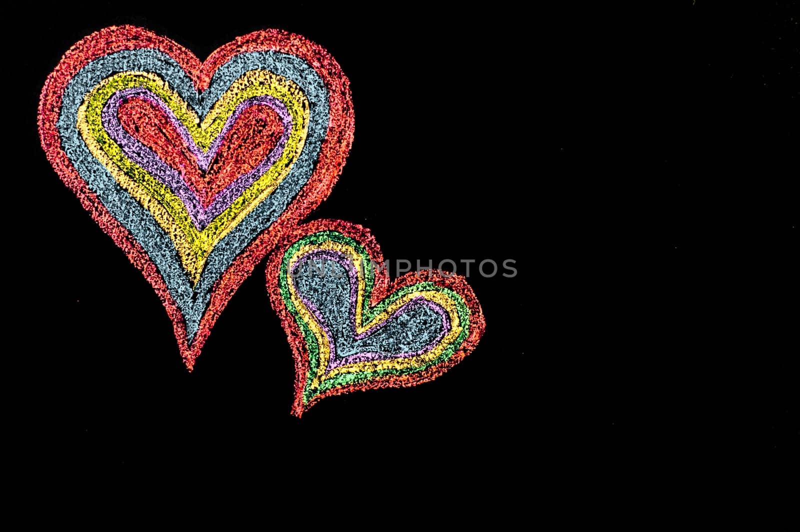 Conceptual image of love, with two vivid color shape hearts close one to each other .Vintage hand drawing on blackboard, isolated on black background, love concept, copy space available