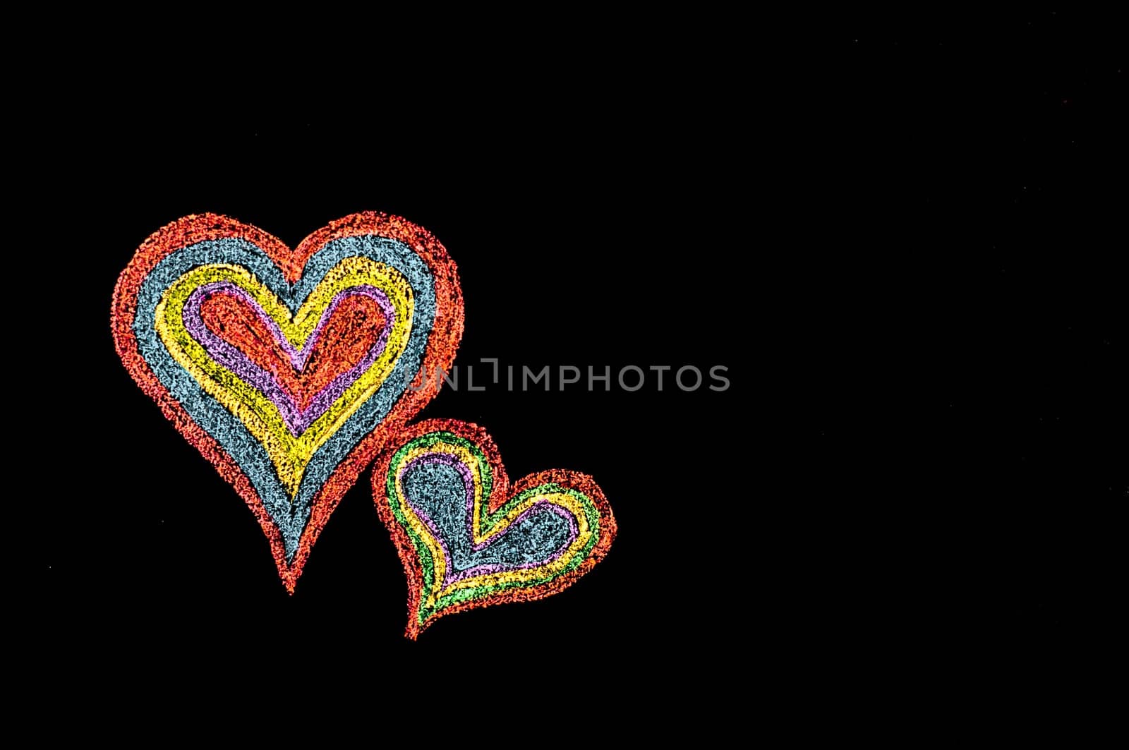 Conceptual image of love, with two vivid color shape hearts close one to each other .Vintage hand drawing on blackboard, isolated on black background, love concept, copy space available