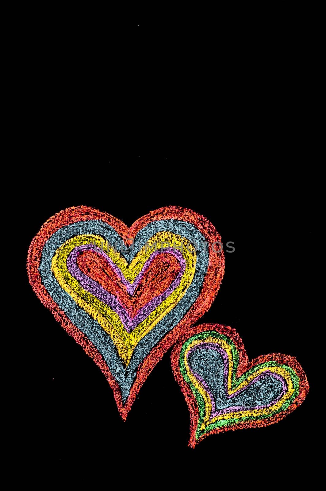 Conceptual image of love, with two vivid color shape hearts close one to each other .Vintage hand drawing on blackboard, isolated on black background, love concept, copy space available