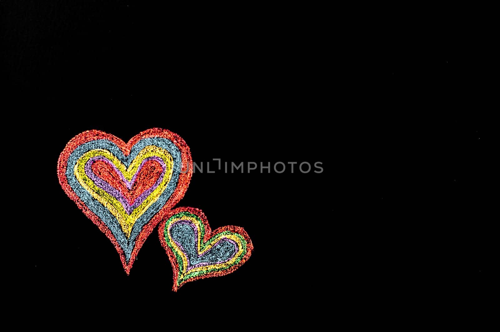Conceptual image of love, with two vivid color shape hearts close one to each other .Vintage hand drawing on blackboard, isolated on black background, love concept, copy space available