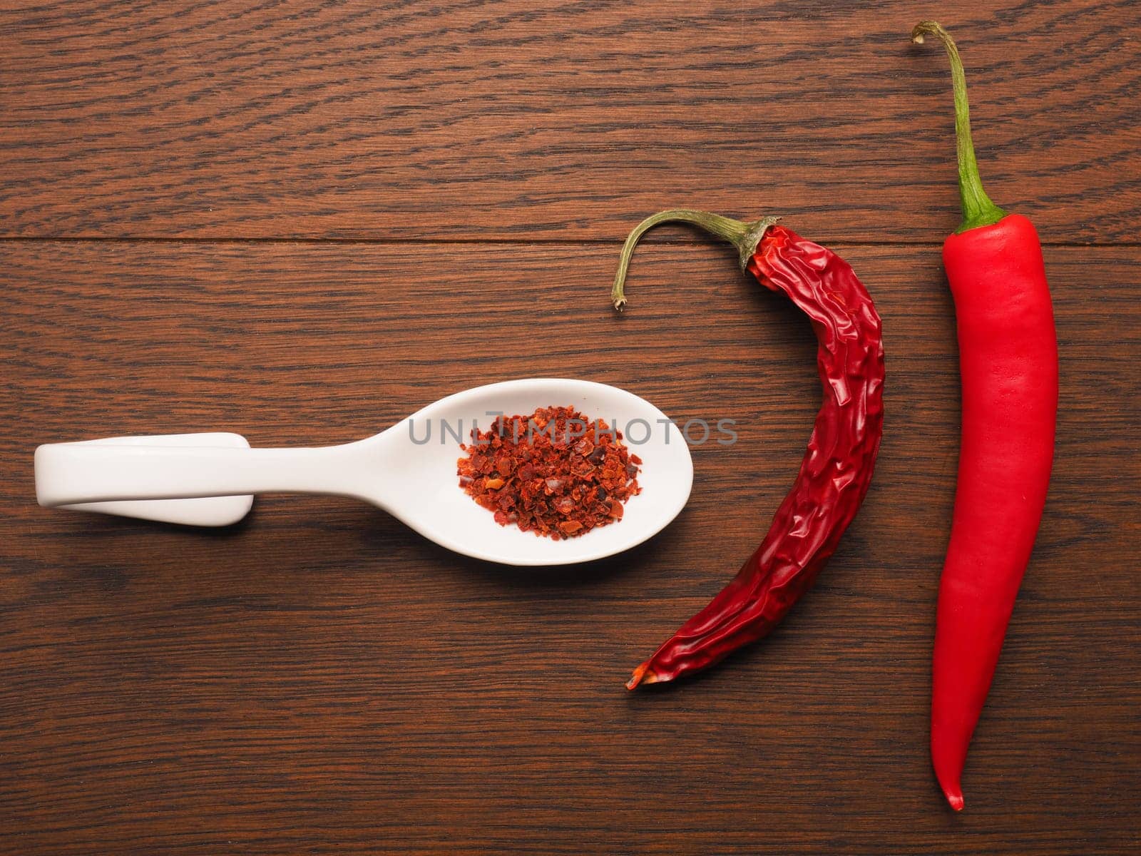 Fresh chili with dried chili and chili flakes on a white spoon