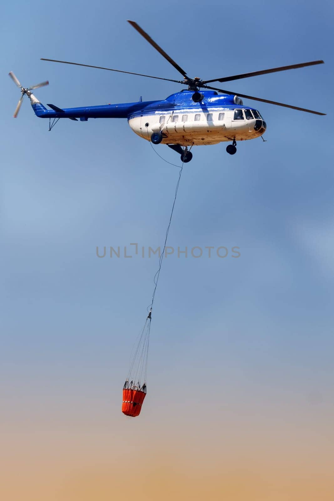 Blue fire rescue helicopter, with water bucket transportation