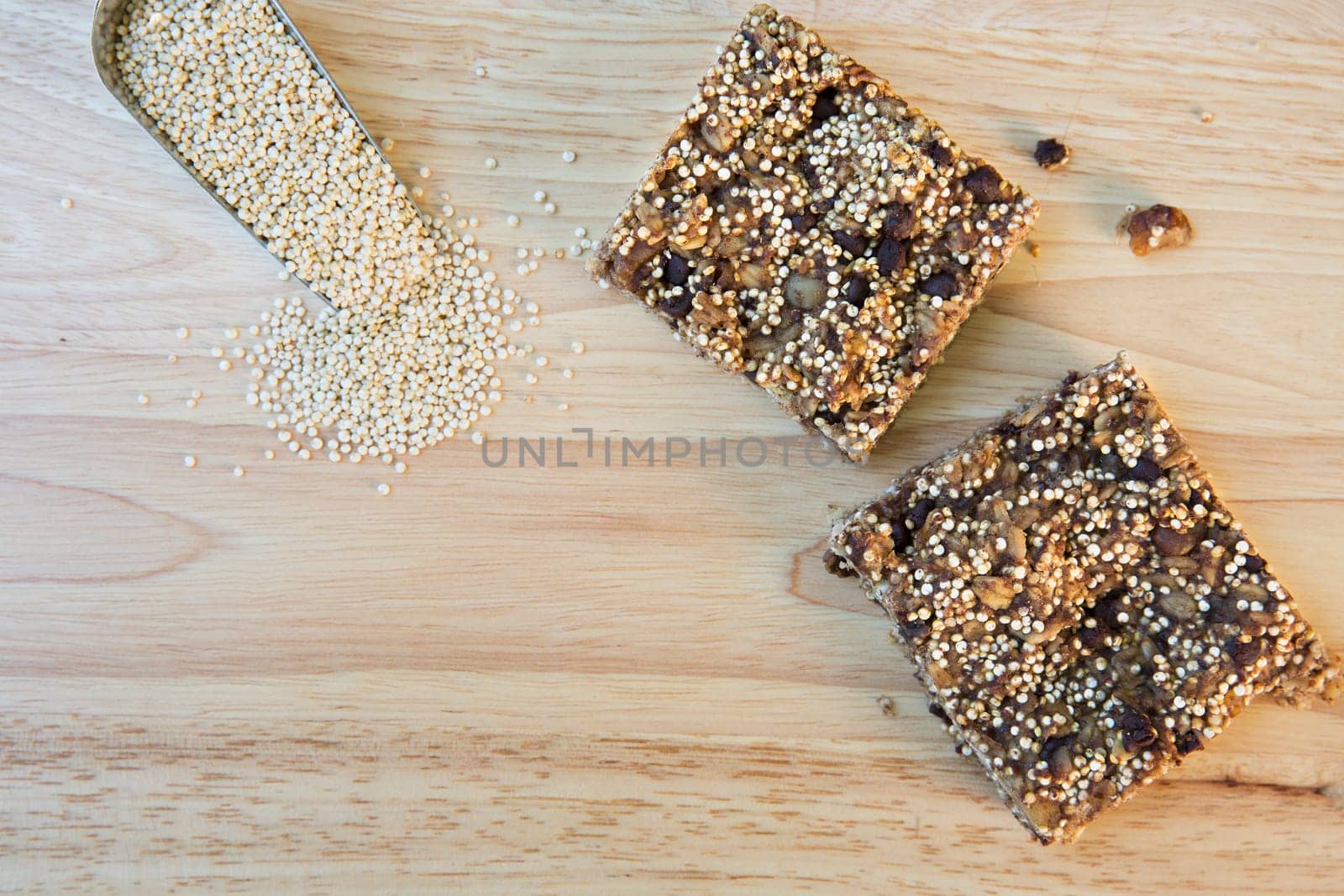 Two quinoa breakfast squares with scoop of raw quinoa and copy space.