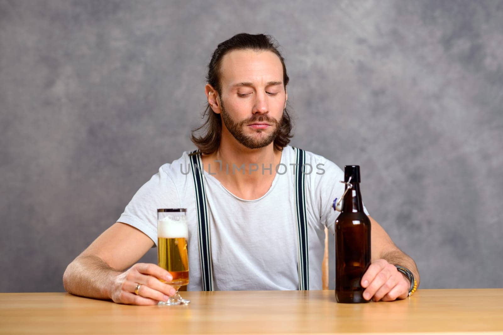 young man in front of gray background drinking beer