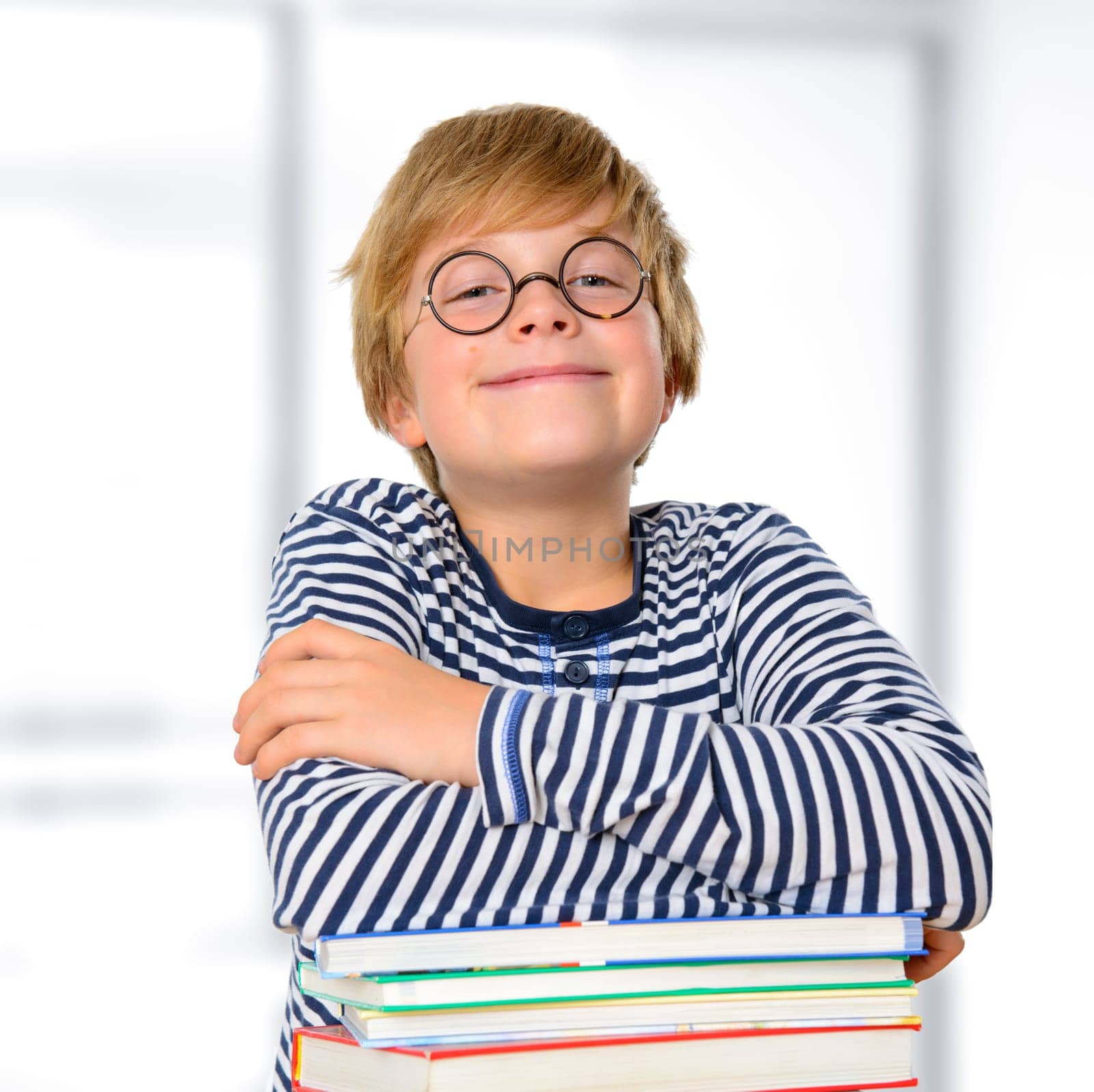 blond boy with round glasses on a pile of books