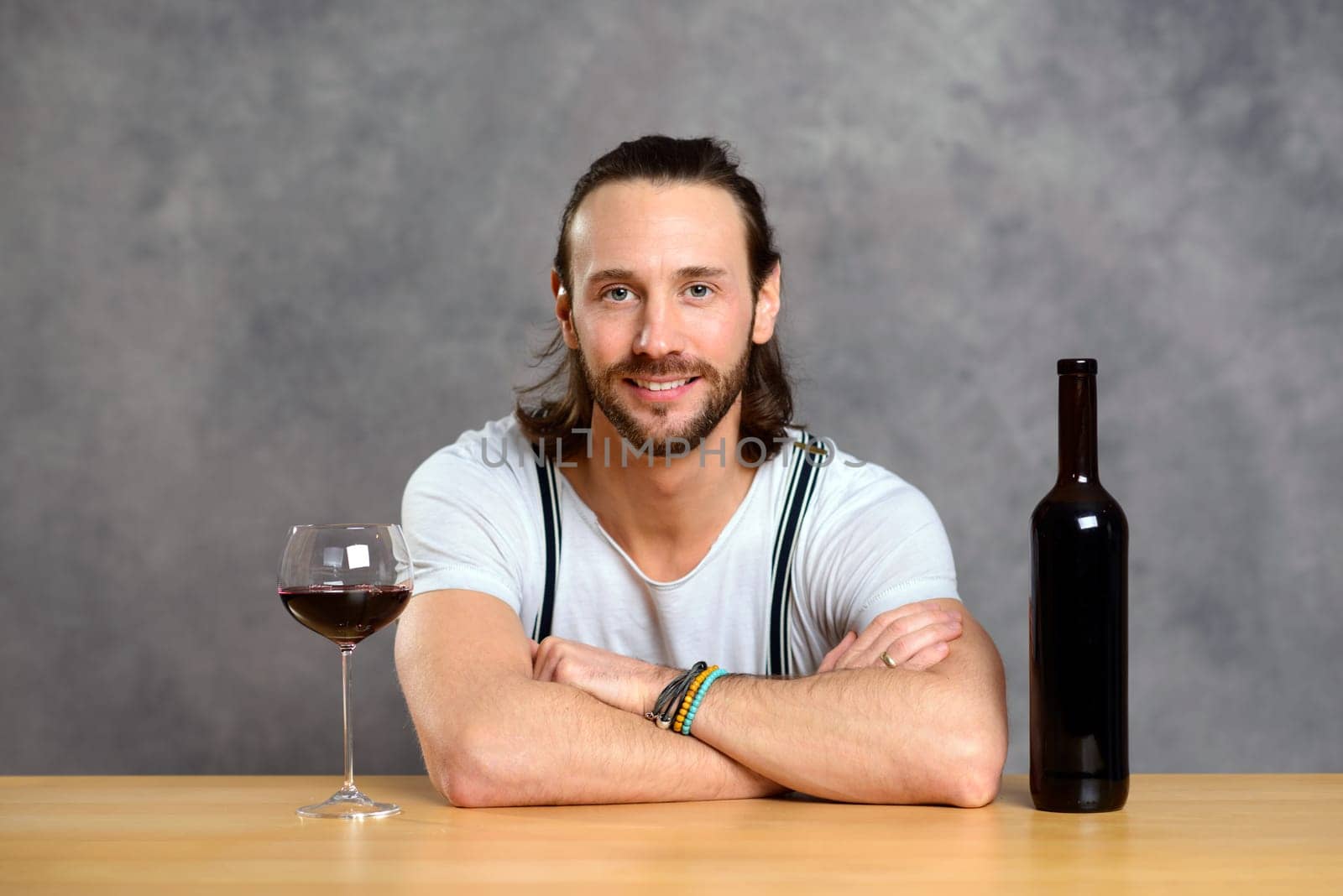 young man in front of gray background drinking red wine