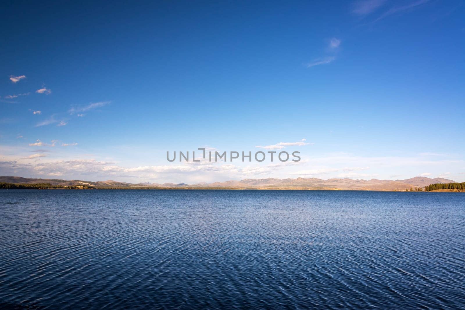 Landscape view of Yellowstone Lake with deep blue water a hills in the background in Yellowstone National Park