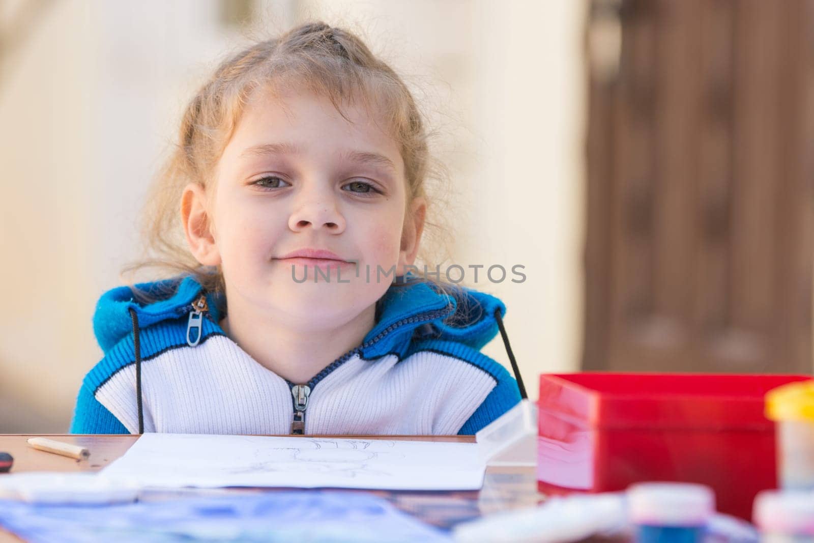 Pretty girls sitting at a table in the courtyard, looked up from the drawing and looked into the frame