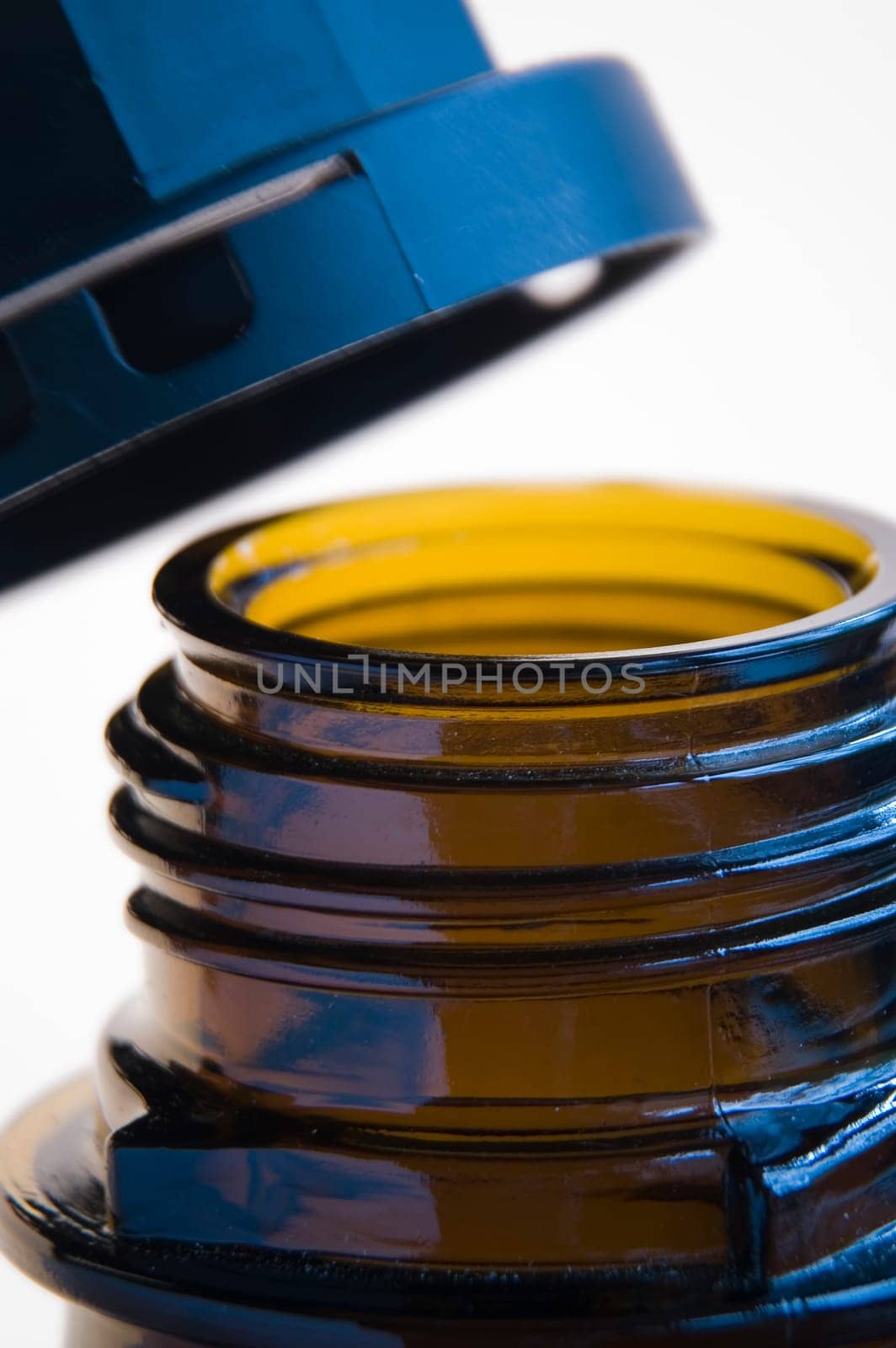 Close-up of a brown bottle neck with open screw cap in front of white