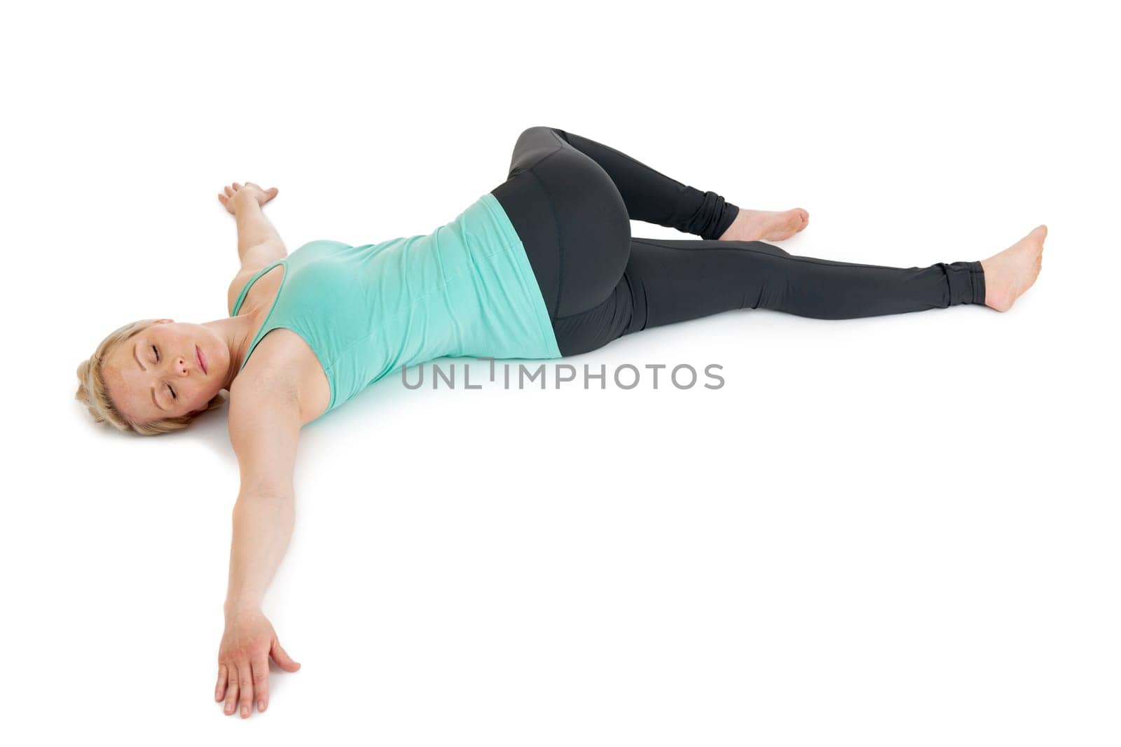 Woman lying on her back with her pelvis twisted to the side and her upper leg overturned. Arms outstretched laterally.