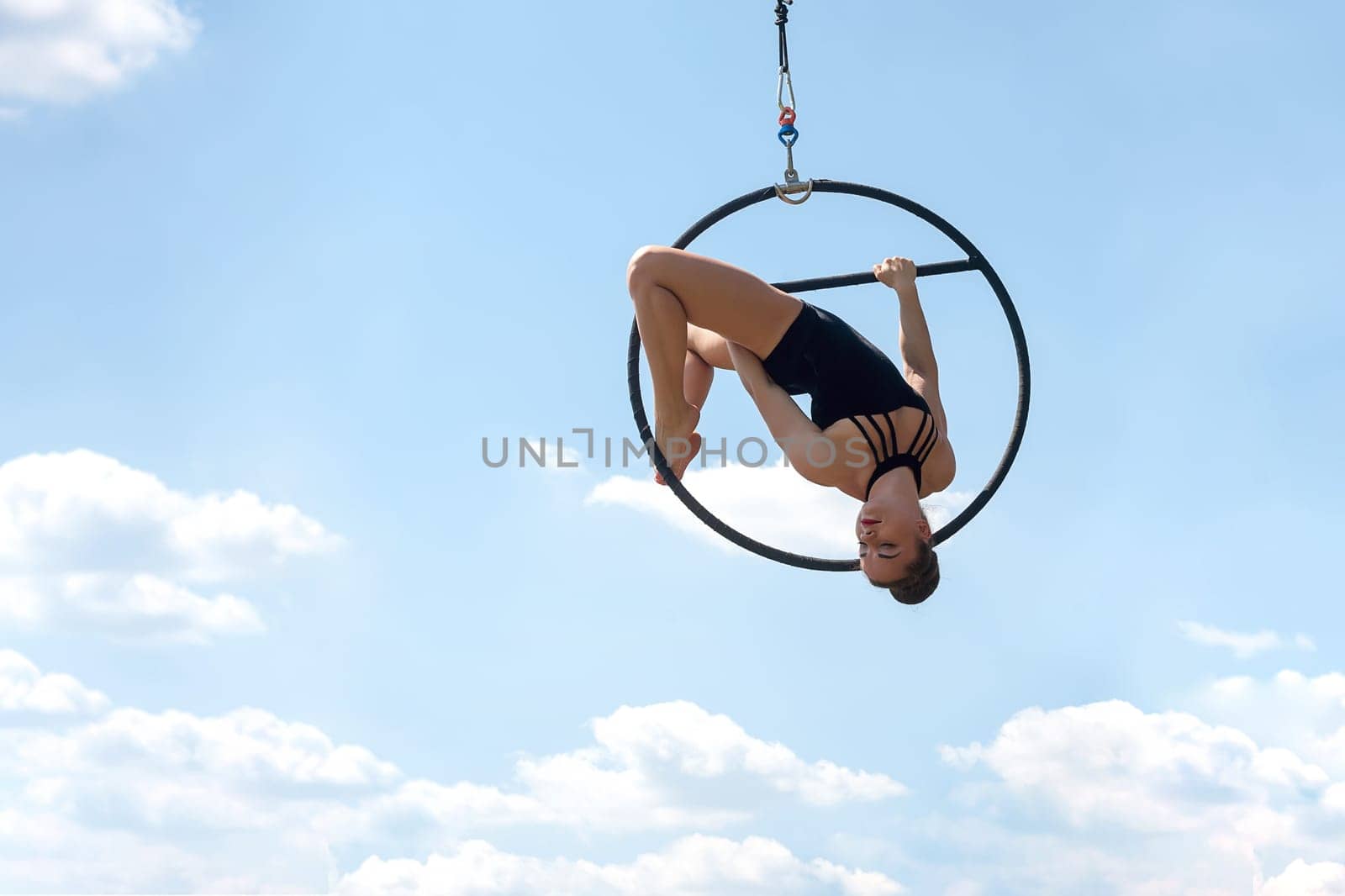 Sport woman doing exercises with a hoop, outdoor, against the blue sky. Sports equipment and lifestyle concept. Antigravity yoga.