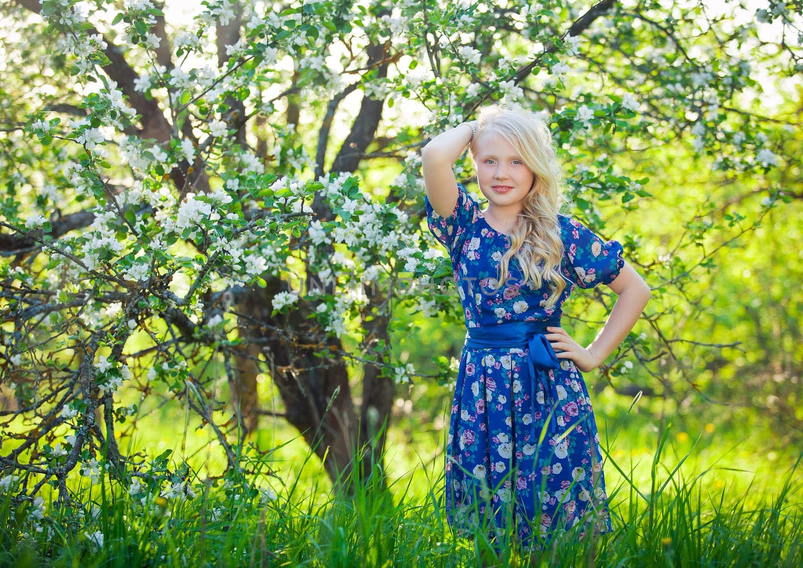 Adorable kid playing in nature. Cute little child, blonde toddler girl playing in blooming cherry garden on beautiful spring or summer day.
