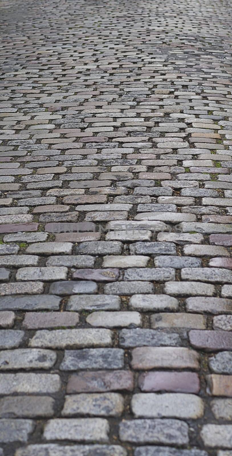Old  traditional european style long narrow  cobblestone road background with granite blocks, stones and brickwork pattern